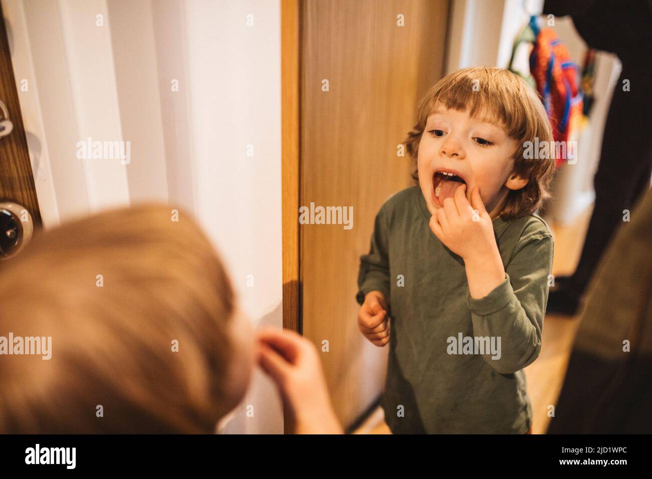 Garçon debout devant le miroir avec la bouche ouverte Banque D'Images