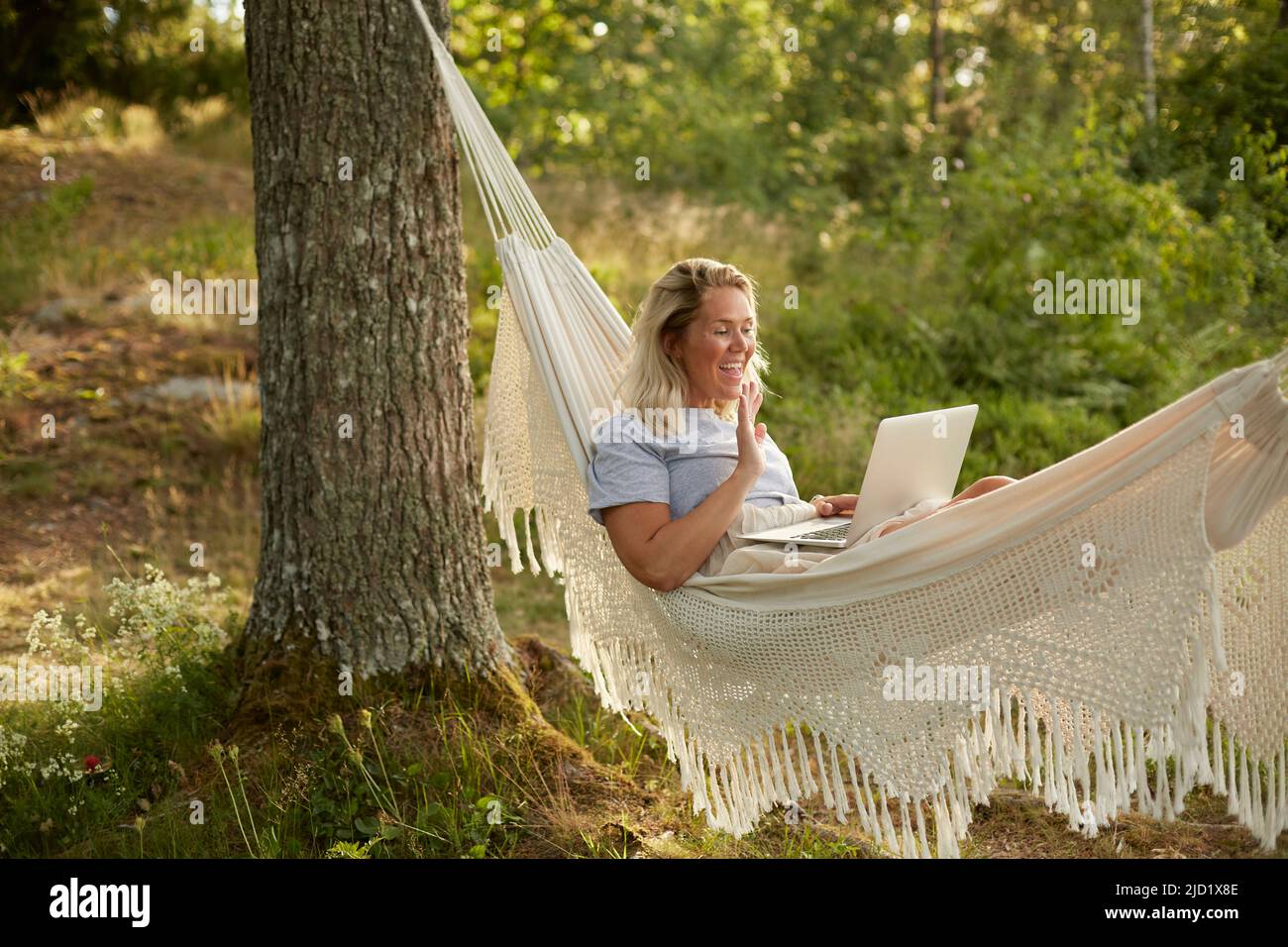 Woman using laptop in hammock Banque D'Images