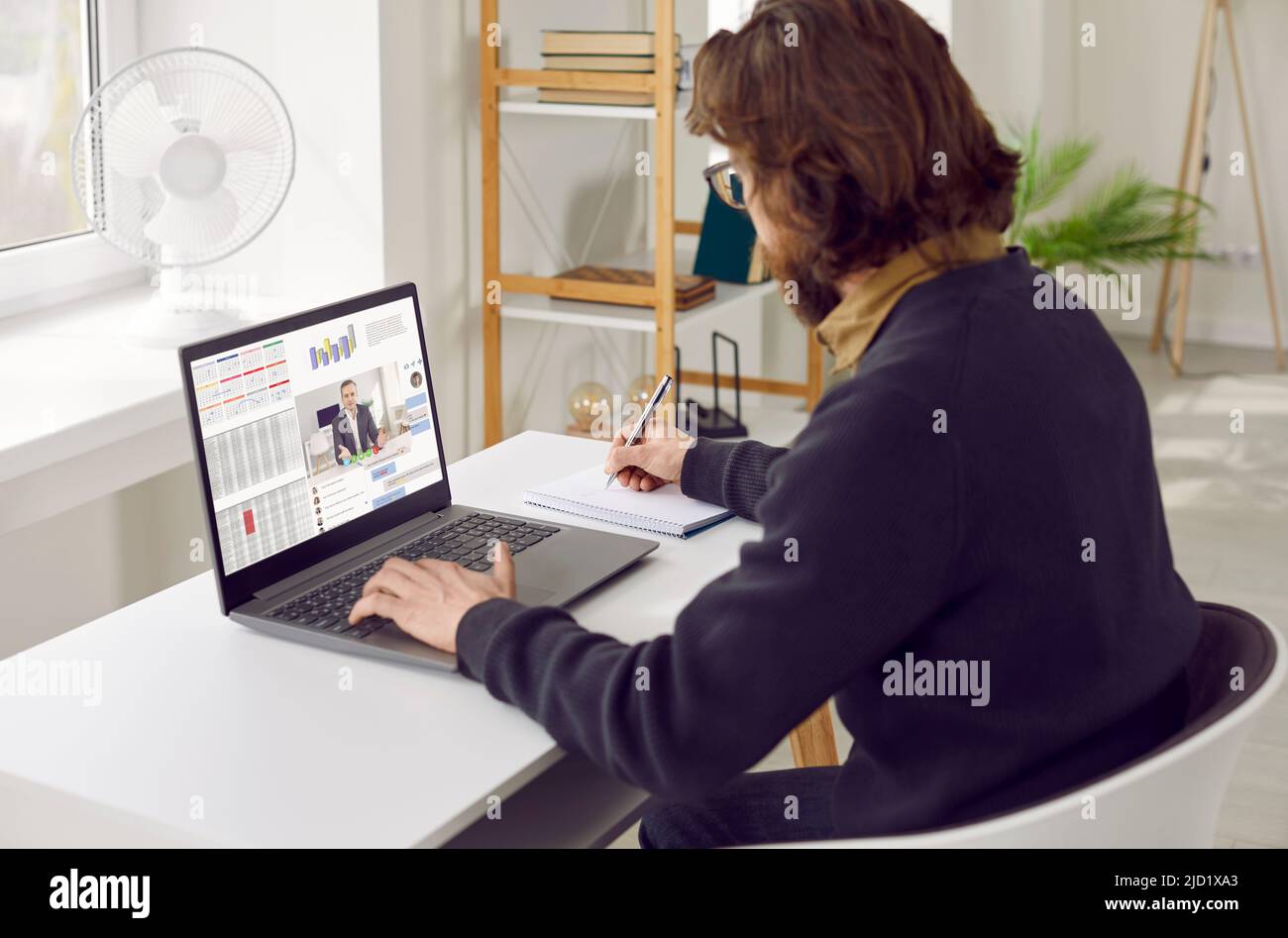 Homme indépendant utilise un ordinateur portable pour participer à des réunions à distance, assis à son bureau à domicile Banque D'Images