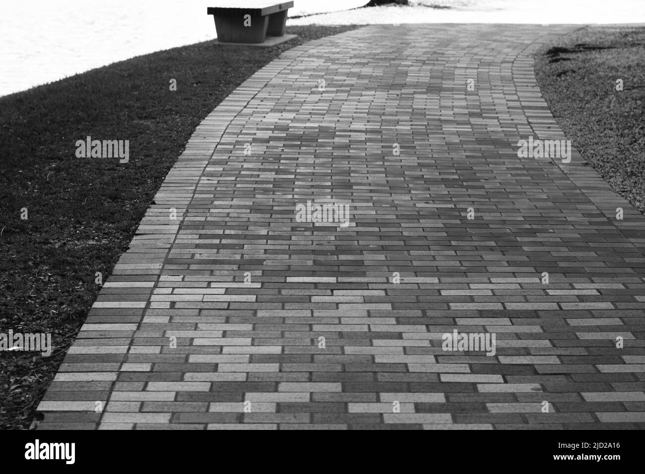 Un trottoir pavé qui s'enroule le long de la ligne de rivage en noir et blanc. Banque D'Images