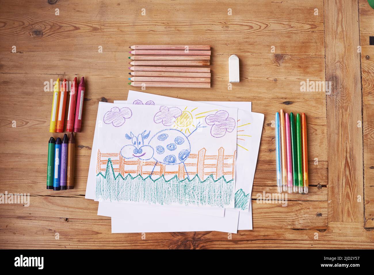 La créativité, c'est l'intelligence qui s'amuse. Photo d'un dessin avec des fournitures de peinture et des crayons sur une table en bois. Banque D'Images