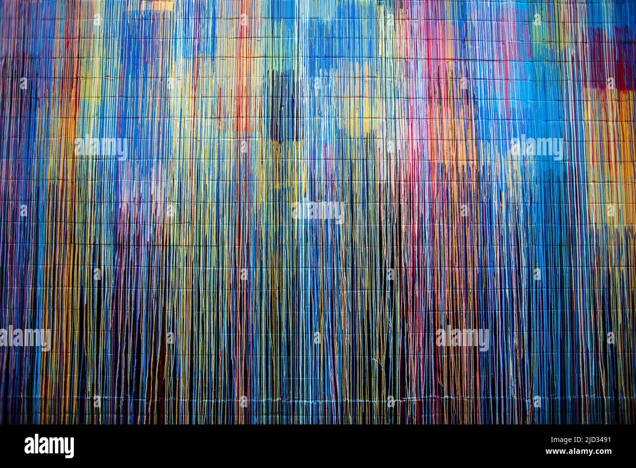 Plusieurs gouttes de peinture colorée stries sur un mur de briques. Banque D'Images