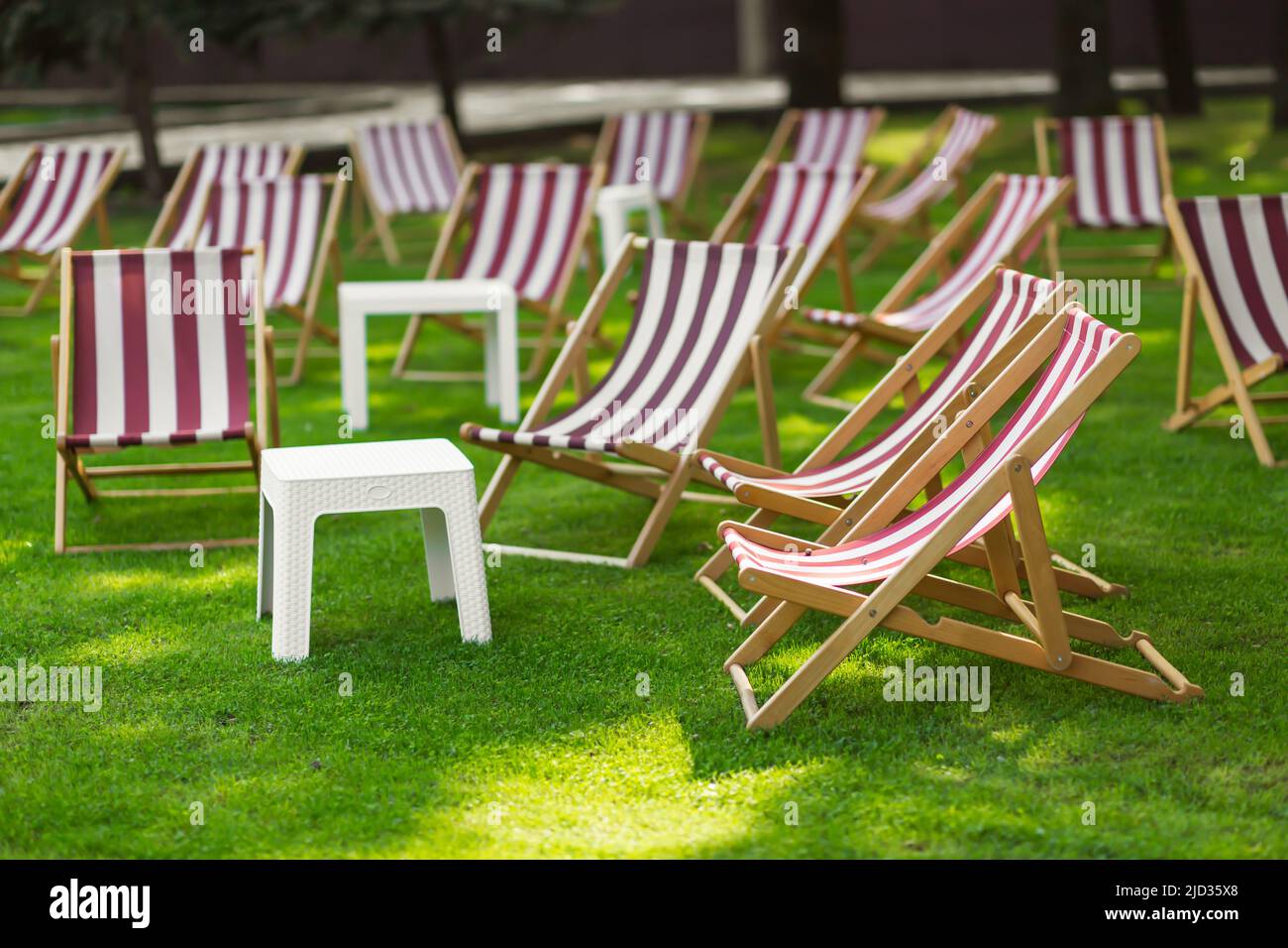Chaises longues à rayures et table dans le parc sur l'herbe. Le concept de loisirs et d'activités de plein air. Banque D'Images
