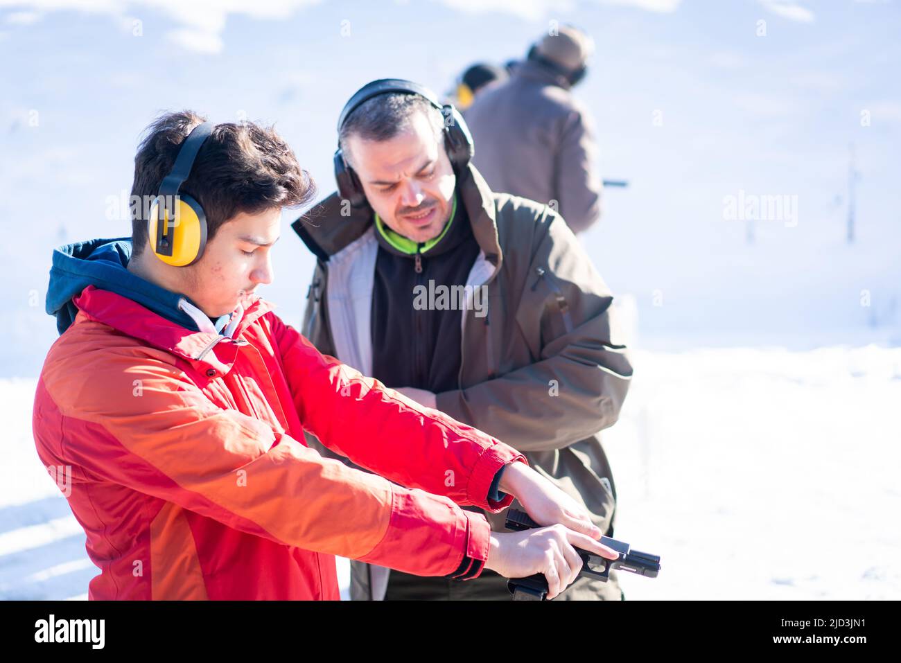 Entraîneur aidant le jeune à viser avec le pistolet à l'entraînement au combat. Photo de haute qualité Banque D'Images