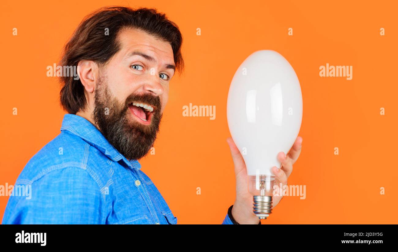 Beau barbu homme dans une chemise en denim avec ampoule. Efficacité énergétique et électricité. Bonne idée Banque D'Images