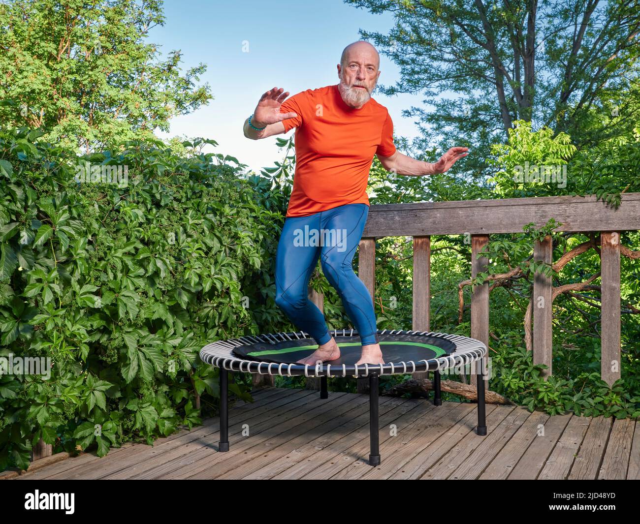 l'homme âgé fait de l'exercice sur un mini trampoline dans une cour arrière, un concept de remise en forme et de rebond Banque D'Images