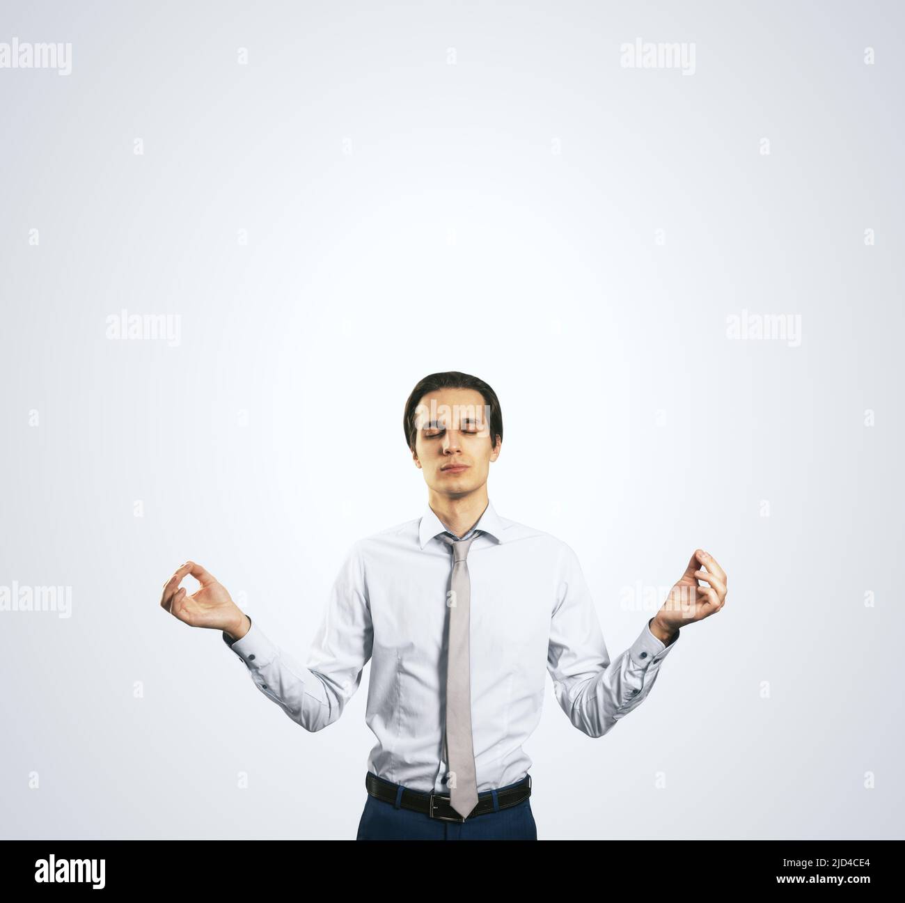 Concept de calme avec homme en chemise blanche dans une posture zen isolée  sur fond gris clair de mur avec un emplacement vide pour votre texte ou  logo, maquette Photo Stock -
