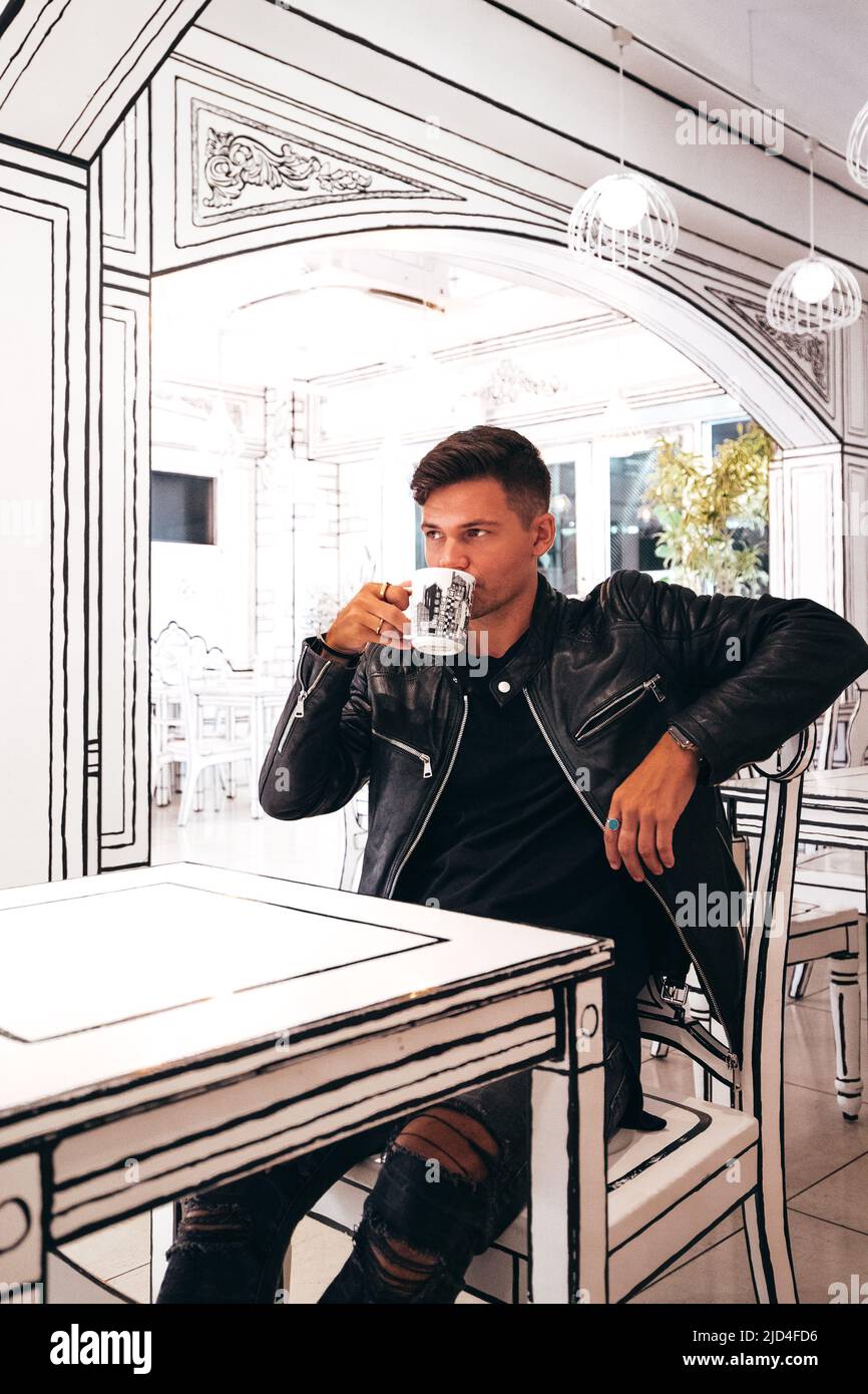 Jeune homme en cuir noir blouson boire du café dans 2D blanc café monochrome Banque D'Images