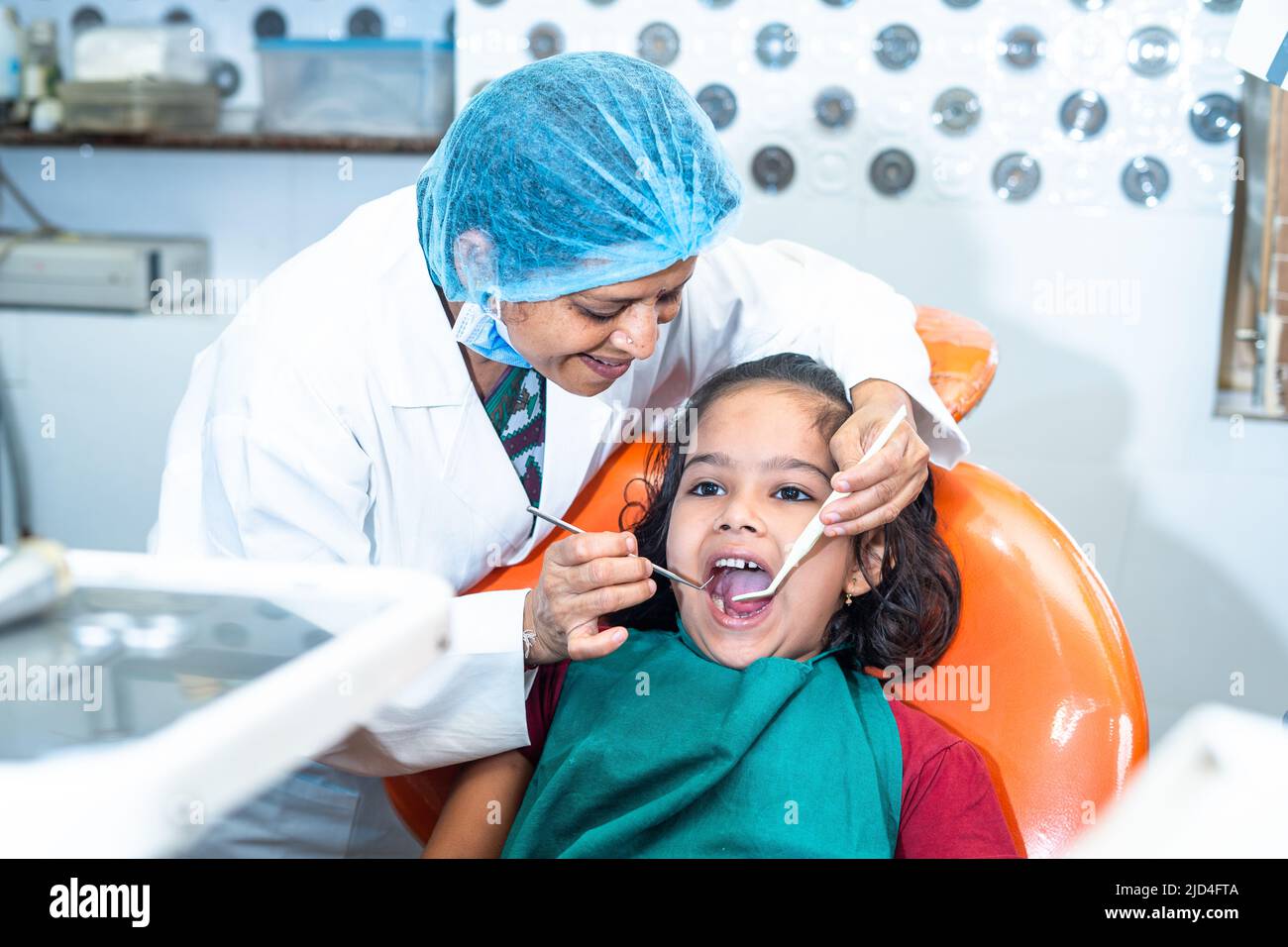 Dentiste souriant traitant la douleur dentaire de l'enfant à l'hôpital - concept de soins dentaires, expertise et hygiéniste. Banque D'Images