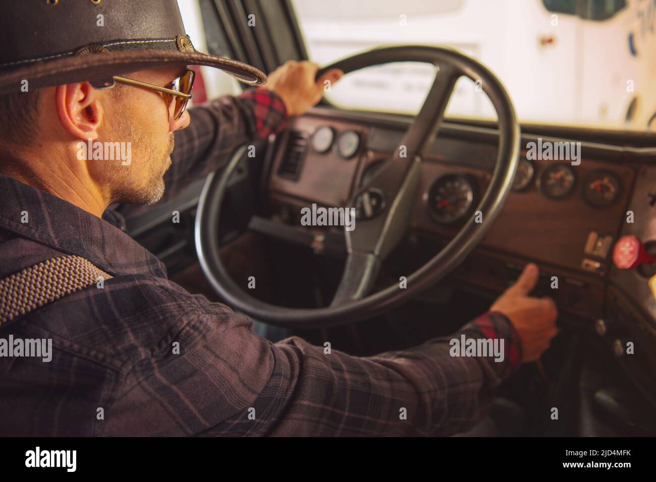 Chauffeur de camion de cow-boy caucasien dans Western Hat et lunettes de soleil se mettre sur la route dans son vieux semi-camion prêt pour un long voyage. Banque D'Images