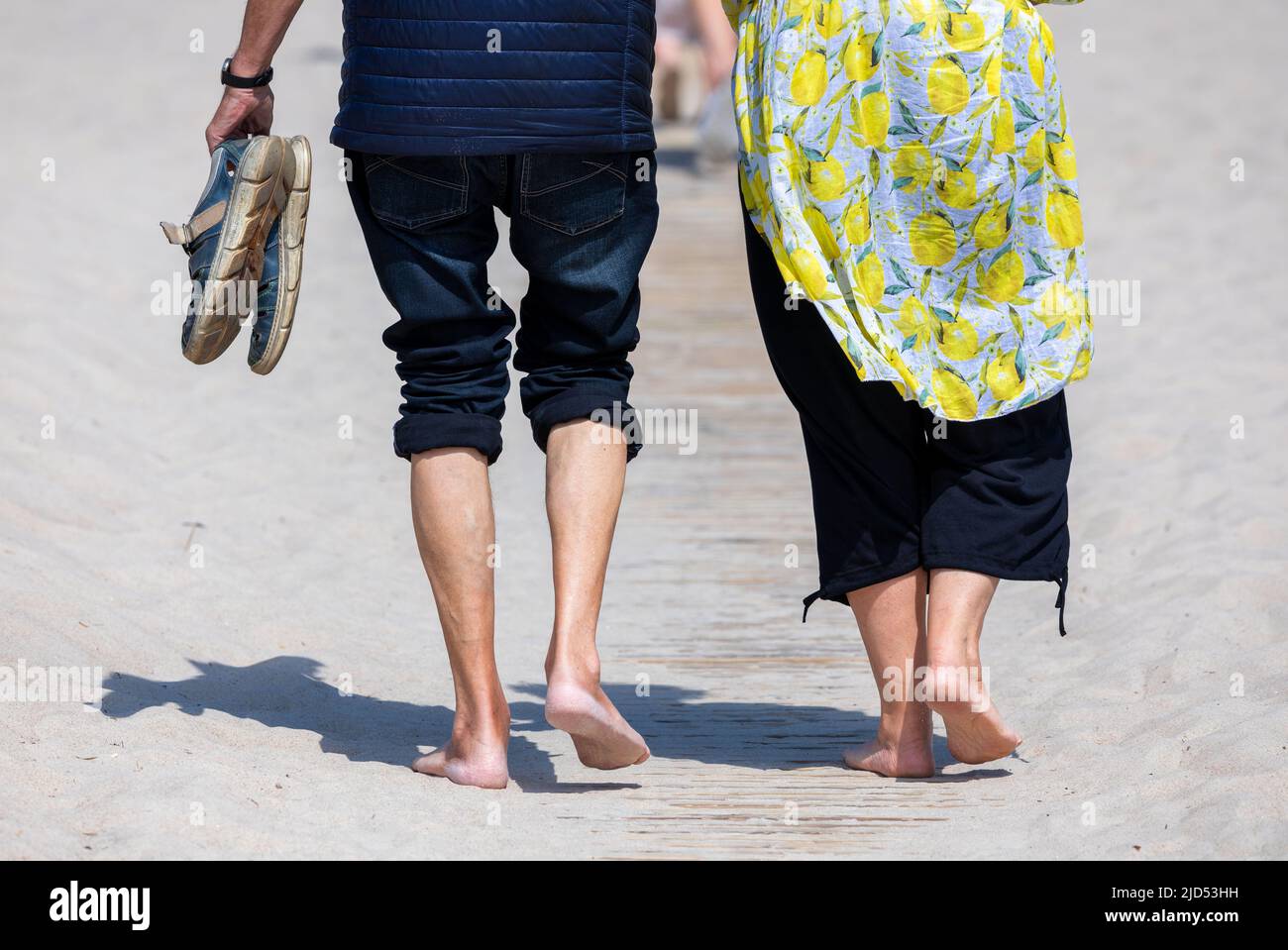 18 juin 2022, Mecklembourg-Poméranie occidentale, Warnemünde: Les vacanciers pieds nus vont à la plage de la mer Baltique par temps ensoleillé. Le temps d'été avec des températures allant jusqu'à 28 degrés assurent des plages bien fréquentées dans le nord. Photo: Jens Büttner/dpa Banque D'Images