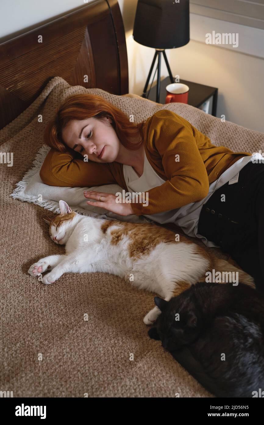 Femme d'âge moyen tenant un chat au gingembre mignon. Femme embrassant son joli petit chaton dans la chambre le soir. Copier l'espace. Adorable animal domestique Banque D'Images