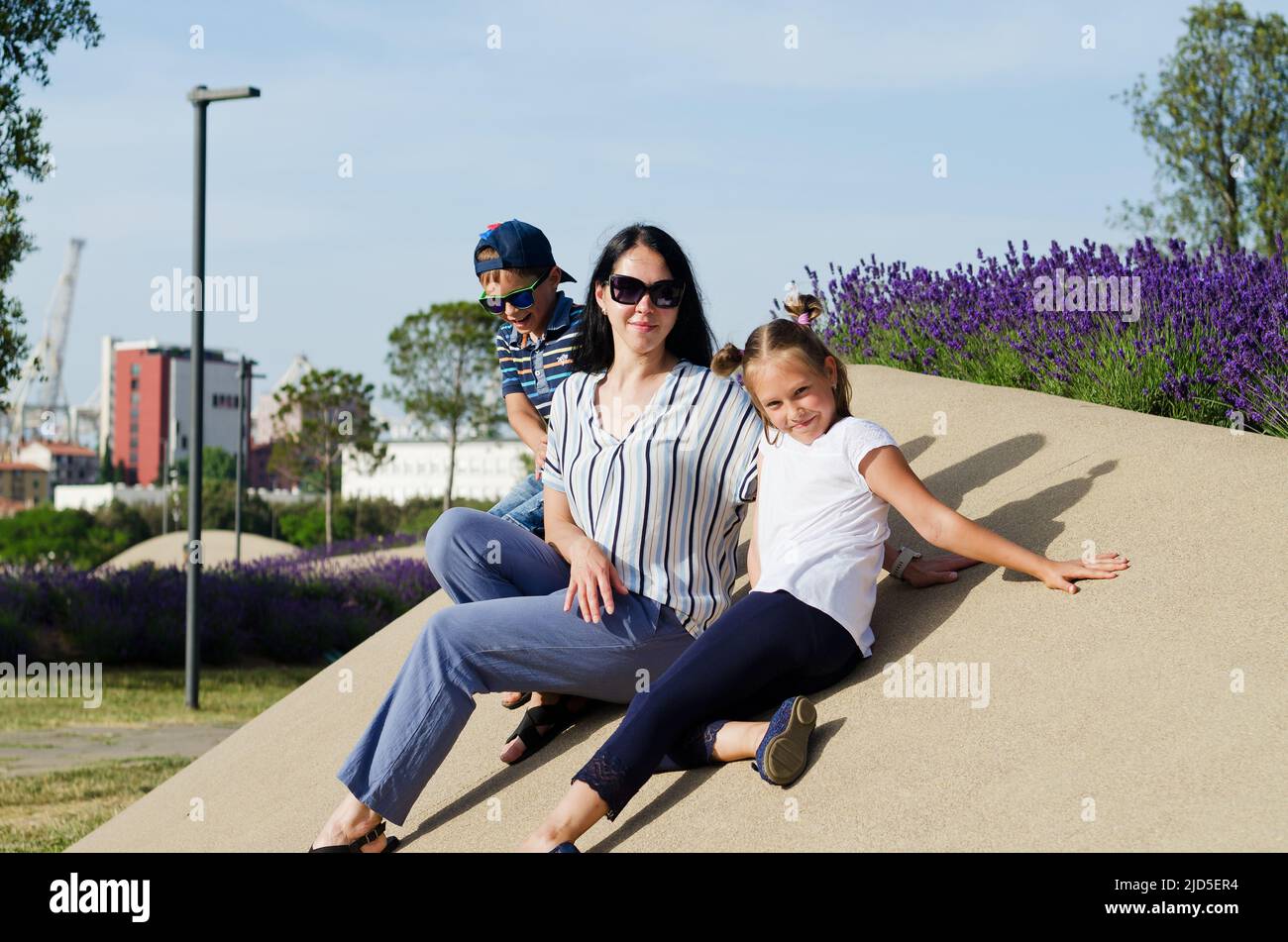 Mode de vie familial et concept de vacances heureux. Mère, petit garçon, fille assise, marche dans la vieille ville, rue. Rire un jour ensoleillé d'été. Amuse-toi bien Banque D'Images