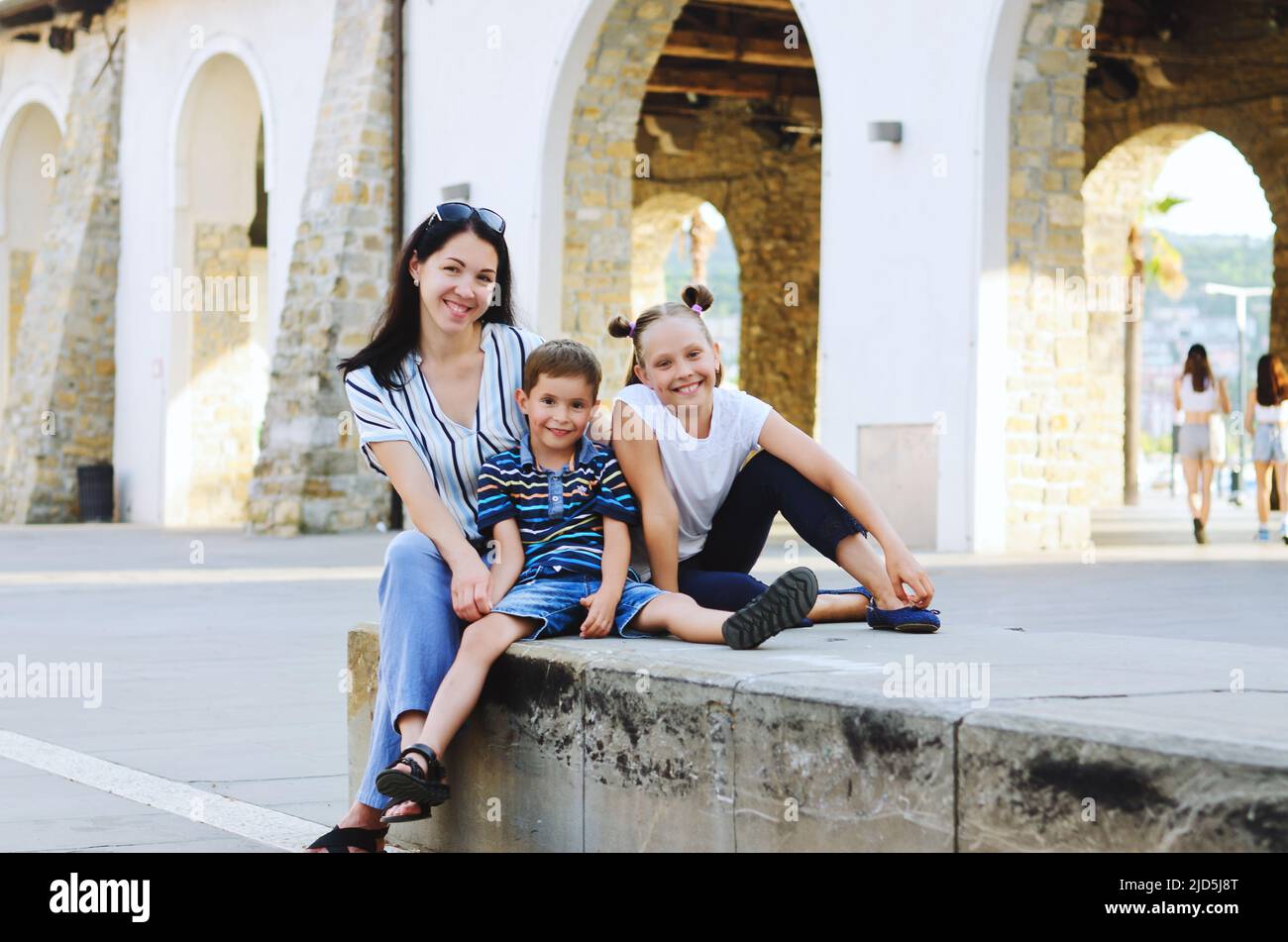 Mode de vie familial et concept de vacances heureux. Mère, petit garçon, fille assise, marche dans la vieille ville, rue. Rire un jour ensoleillé d'été. Amuse-toi bien Banque D'Images