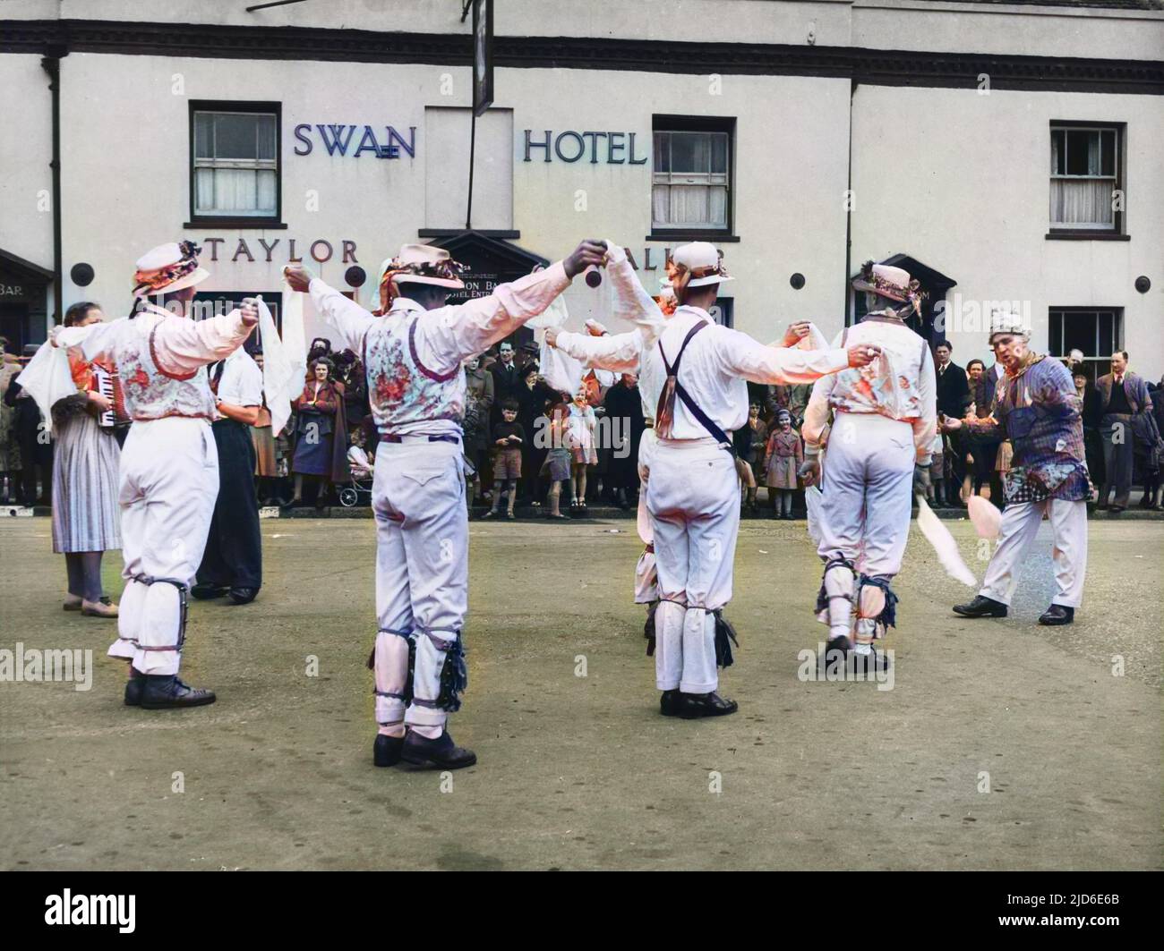MORRIS DANSE: Thaxted, Essex. Les villageois se rassemblent à l'extérieur du Swan Hotel pour assister à une exécution de l'équipe de danse morris. Certains des danseurs sport gilets avec motifs floraux version colorisée de : 10089750 Date: 1950s Banque D'Images