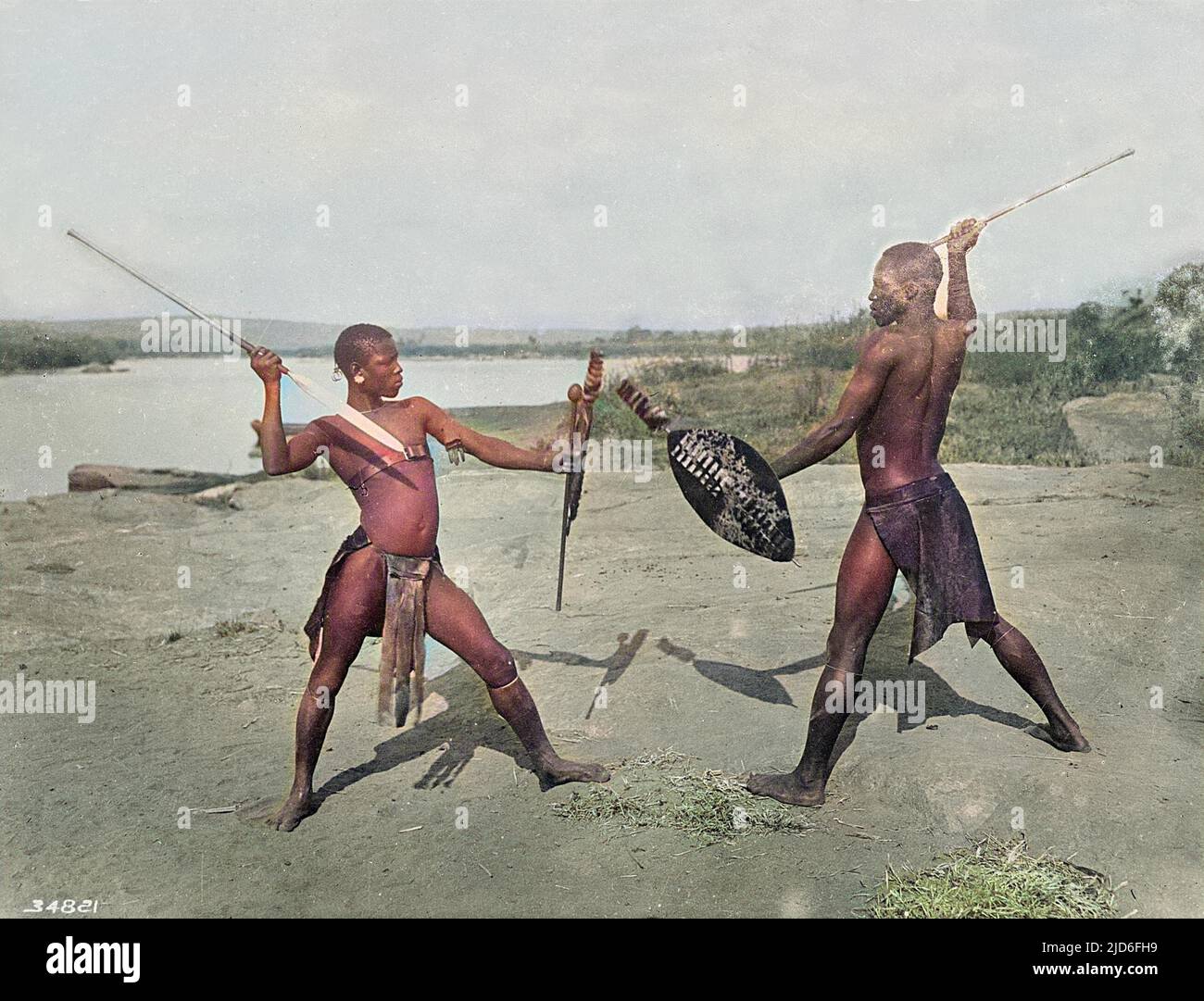 Deux guerriers zoulou sur une plage, jouent avec des épées et des boucliers dans leurs loin. Version colorisée de : 10165262 Date : début 1930s Banque D'Images