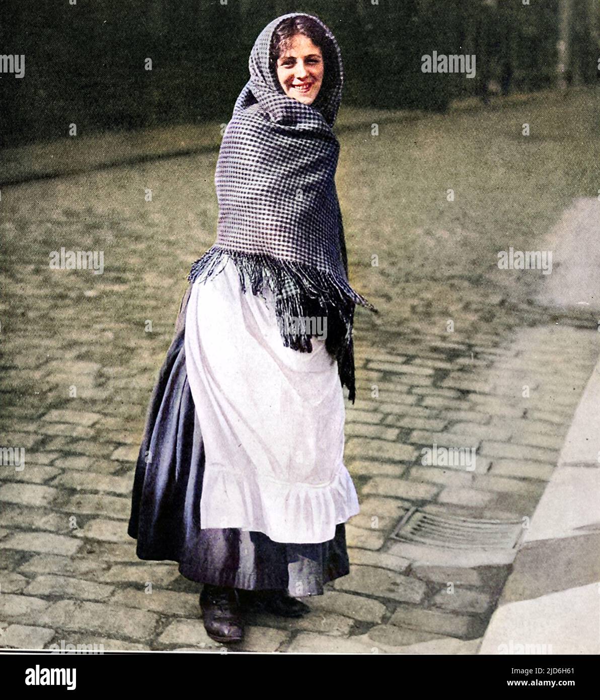 Un ouvrier du coton du Lancashire s'est enveloppé de châles et portait des sabots marchant le long d'une rue pavée d'Oldham. Version colorisée de : 10216172 Date: 1910 Banque D'Images