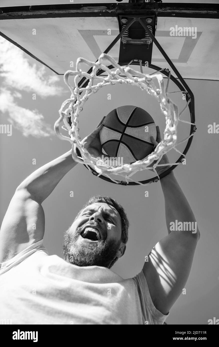 homme joueur réussi lancer ballon de basket-ball à travers le panier, succès Banque D'Images