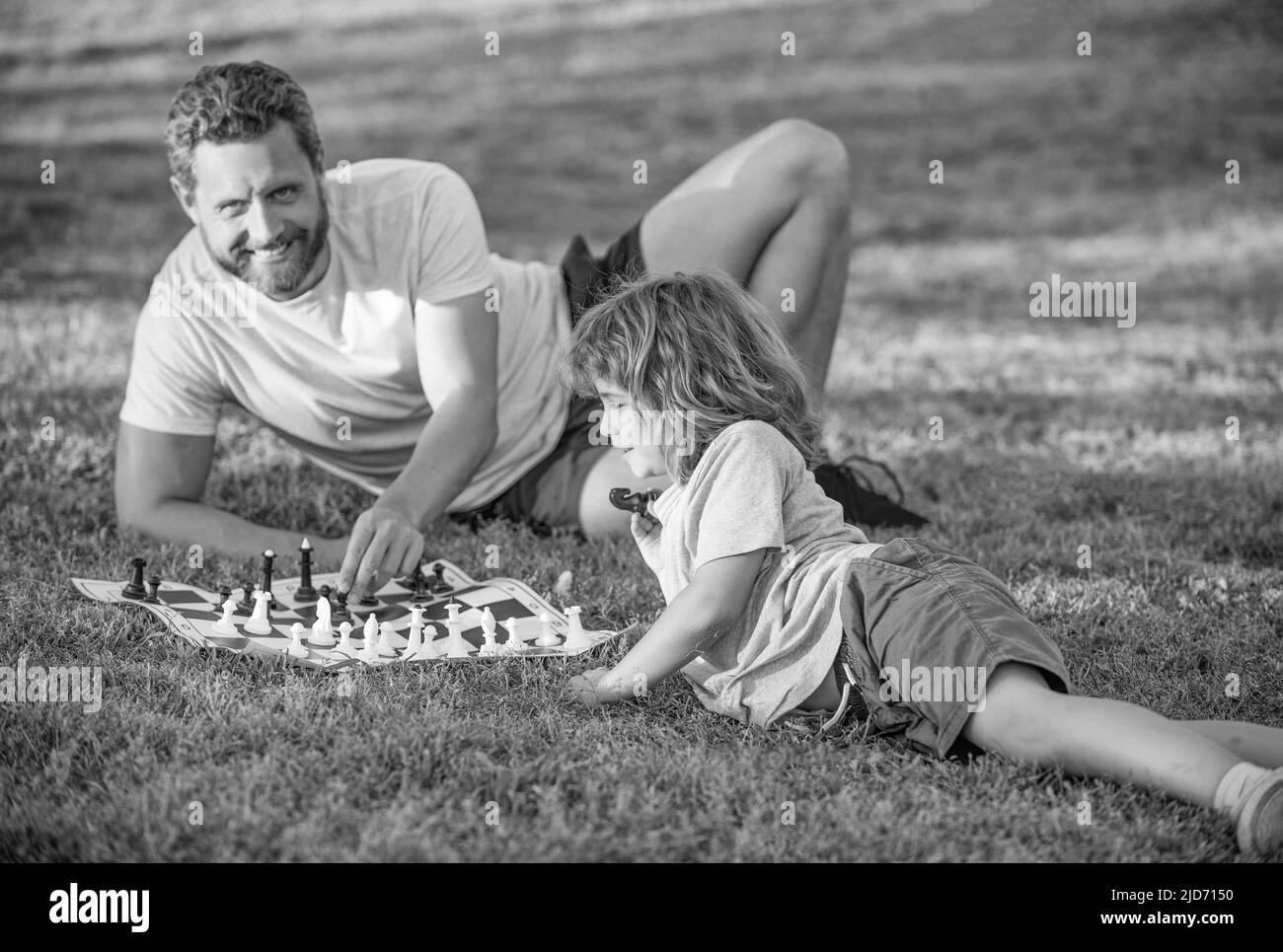 bonne famille de papa et son enfant jouant aux échecs sur l'herbe verte dans le parc extérieur, checkmate Banque D'Images