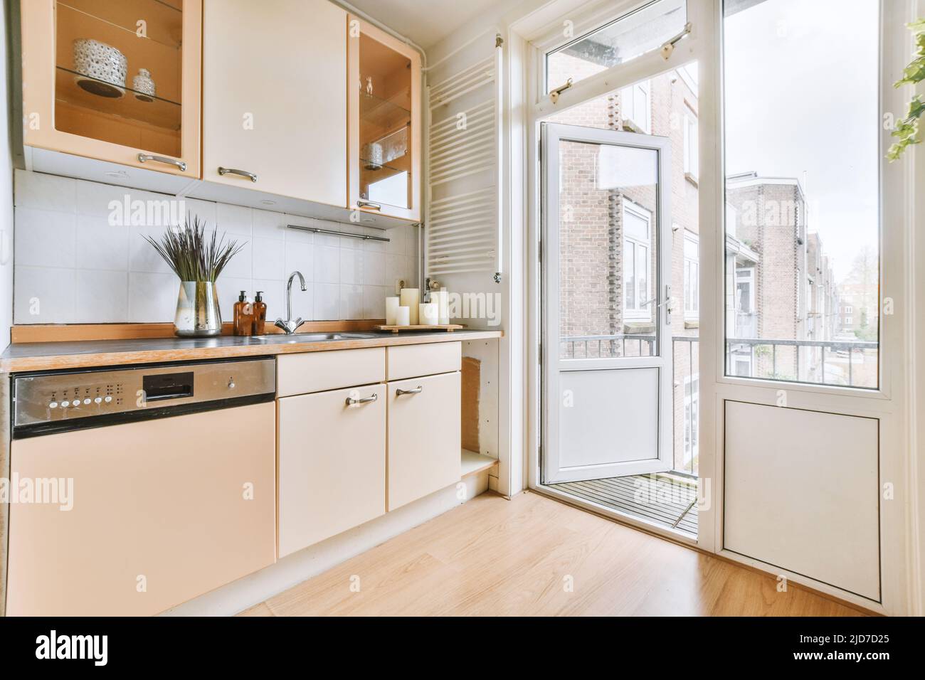 Intérieur d'une cuisine lumineuse avec mobilier beige et portes-balcons dans un appartement moderne Banque D'Images