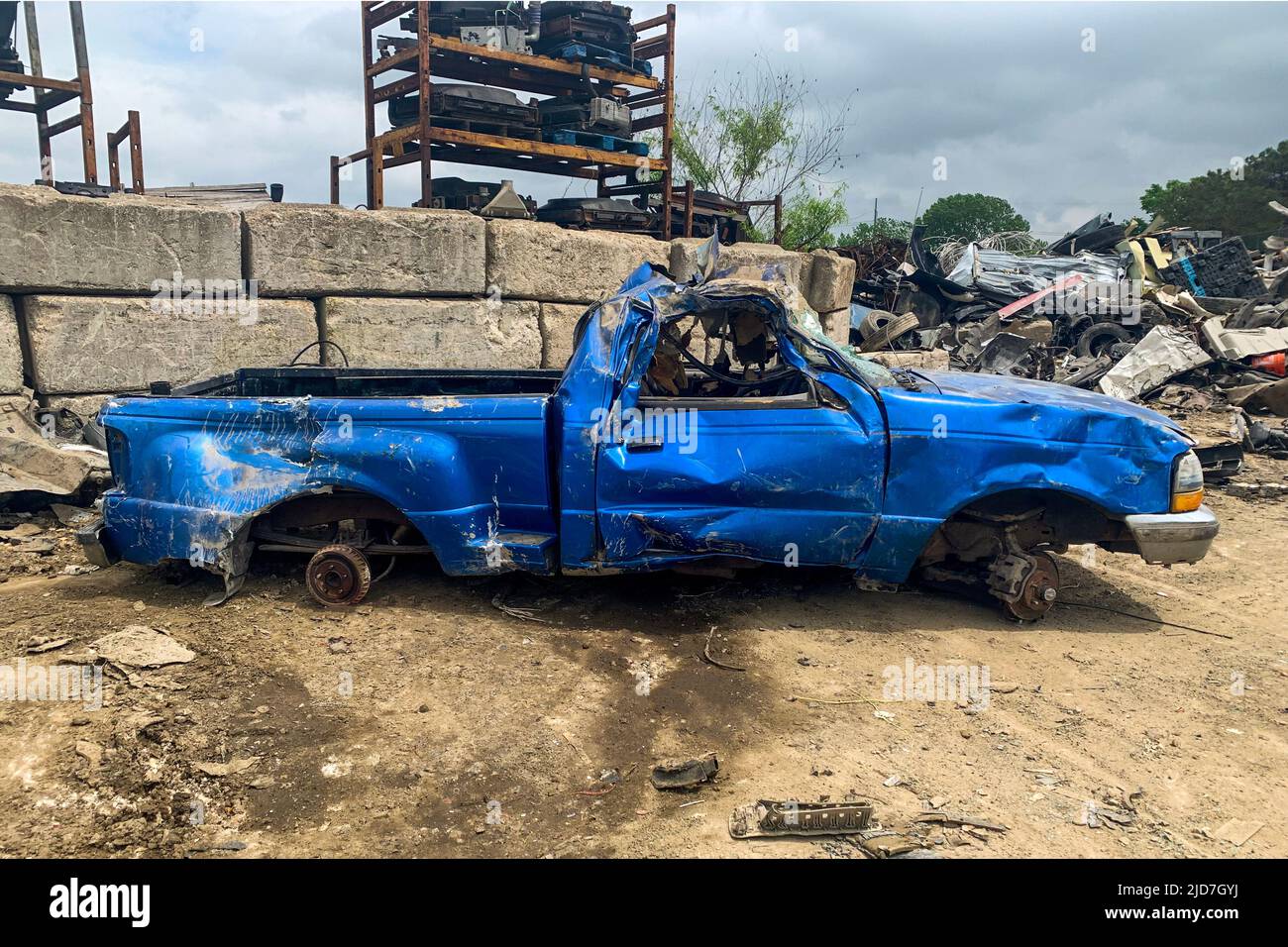 Vue latérale d'un pick-up bleu endommagé sans roues sur le chantier naval après un accident de voiture sur une route, cimetière de voitures, recyclage des automobiles cassées Banque D'Images