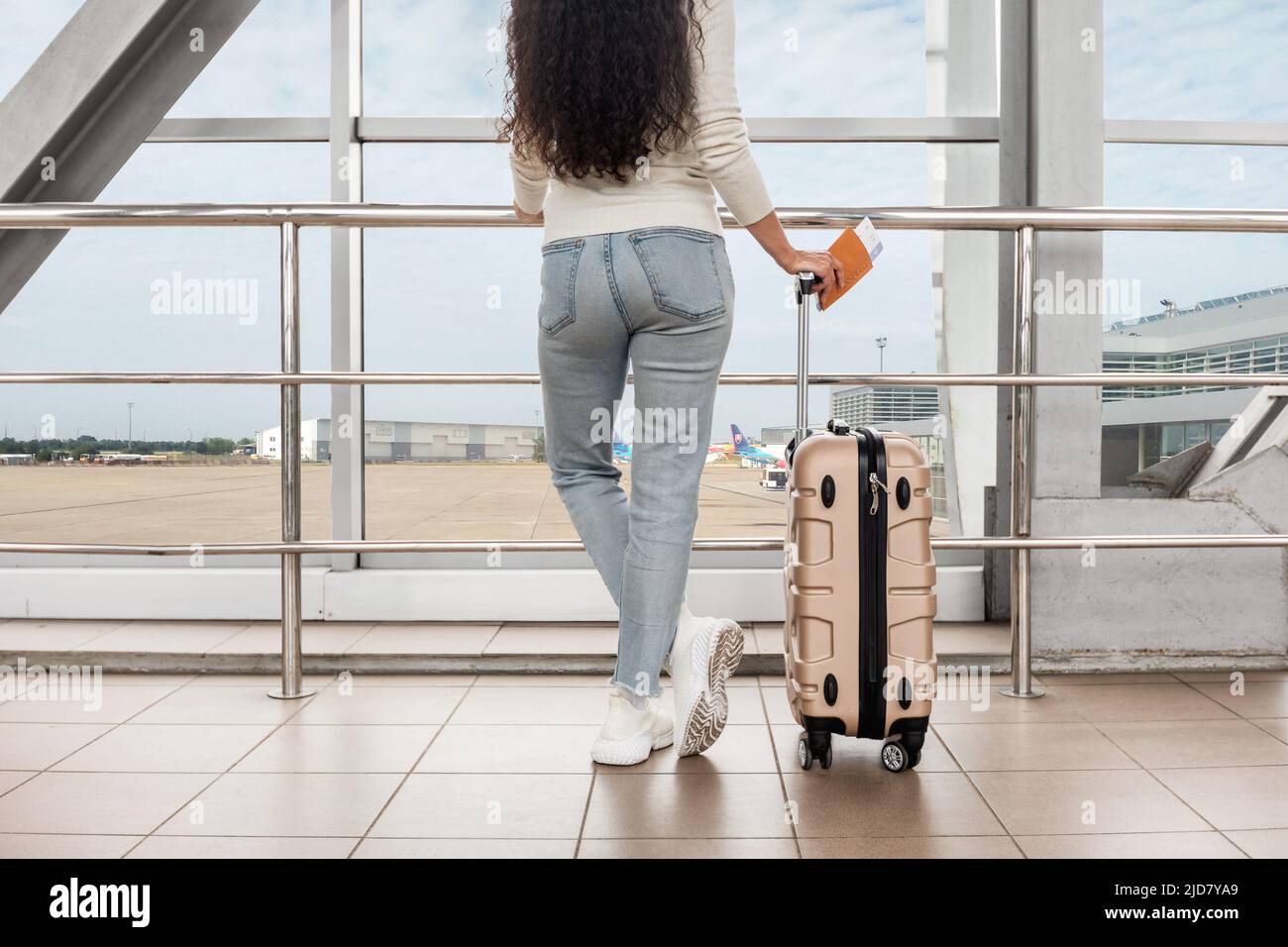 Prise de vue rognée d'une jeune femme debout avec une valise près de la fenêtre de l'aéroport Banque D'Images