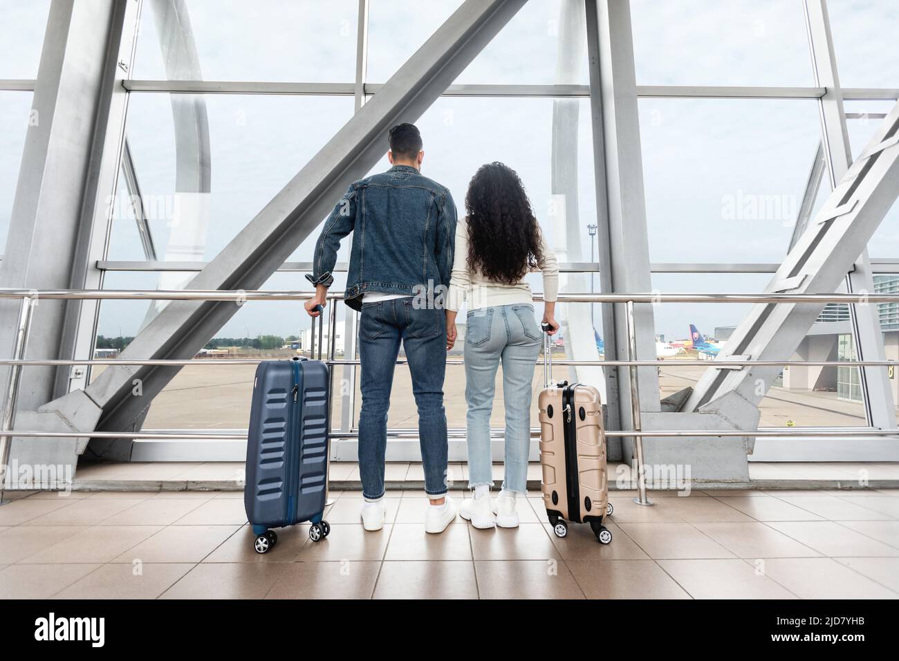 Voyagez ensemble. Vue arrière du jeune couple en attente de vol à l'aéroport, Banque D'Images