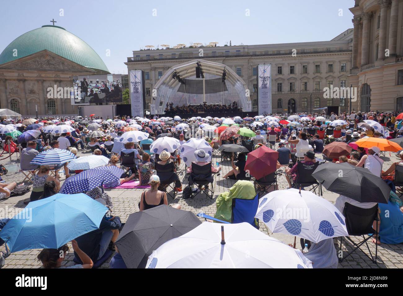 19 juin 2022, Berlin: De nombreuses personnes qui sont venues à l'Opéra de Sate pour tous sur Bebelplatz se protègent de la chaleur avec des parasols. Photo: Joerg Carstensen/dpa Banque D'Images