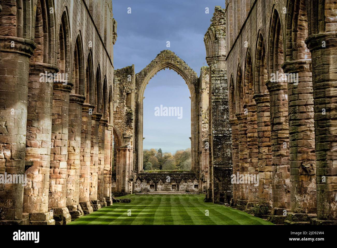 L'église Nave à l'abbaye de Fountains avec des rangées de piliers circulaires et une fenêtre voûtée, Ripon, Angleterre, Royaume-Uni. Banque D'Images