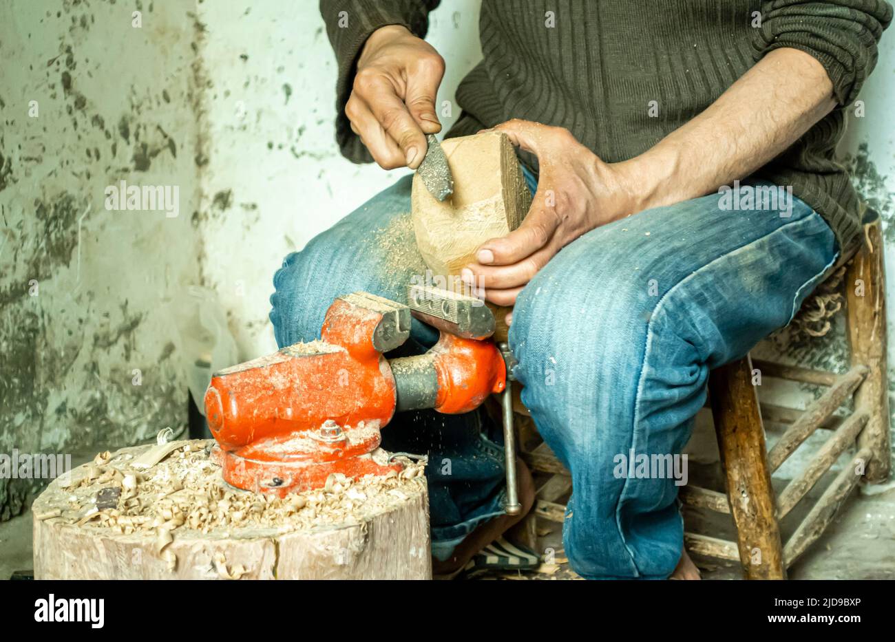 Un maître d'instrument de musique qui dépose un morceau de bois utilisé comme base pour un guembri, dans son atelier. Artisans à Marrakech, Maroc, Afrique du Nord Banque D'Images