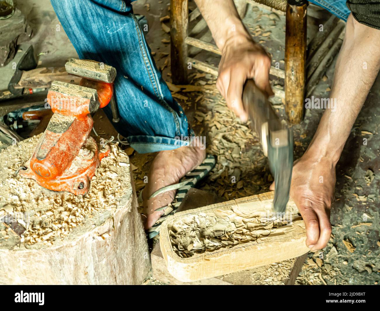 Un maître d'instrument de musique ciselant un morceau de bois utilisé comme base pour un guembri, dans son atelier. Artisans à Marrakech, Maroc, Afrique du Nord Banque D'Images
