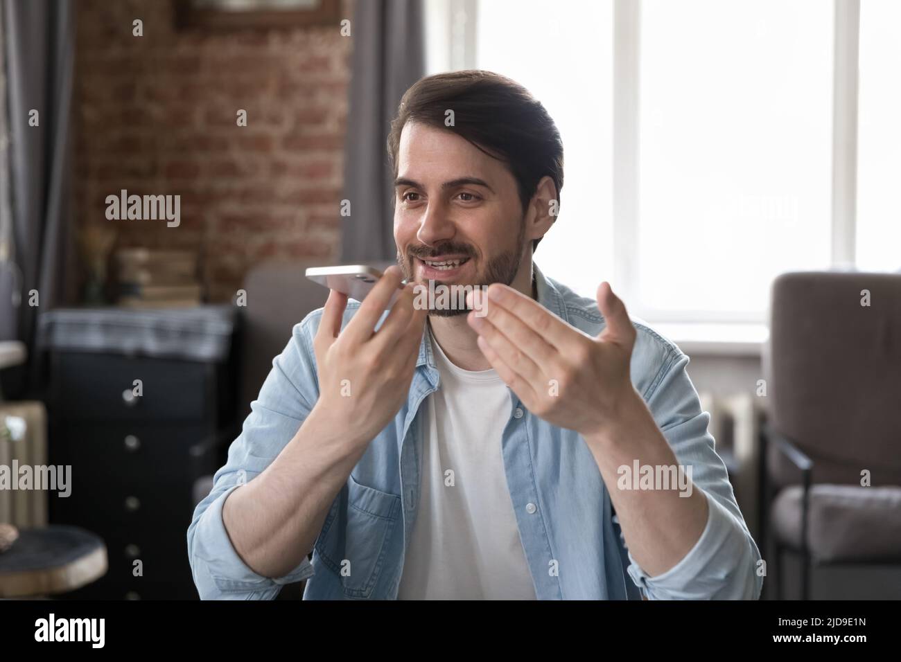 Homme d'affaires tenant un smartphone parle sur un téléphone à haut-parleur au bureau Banque D'Images