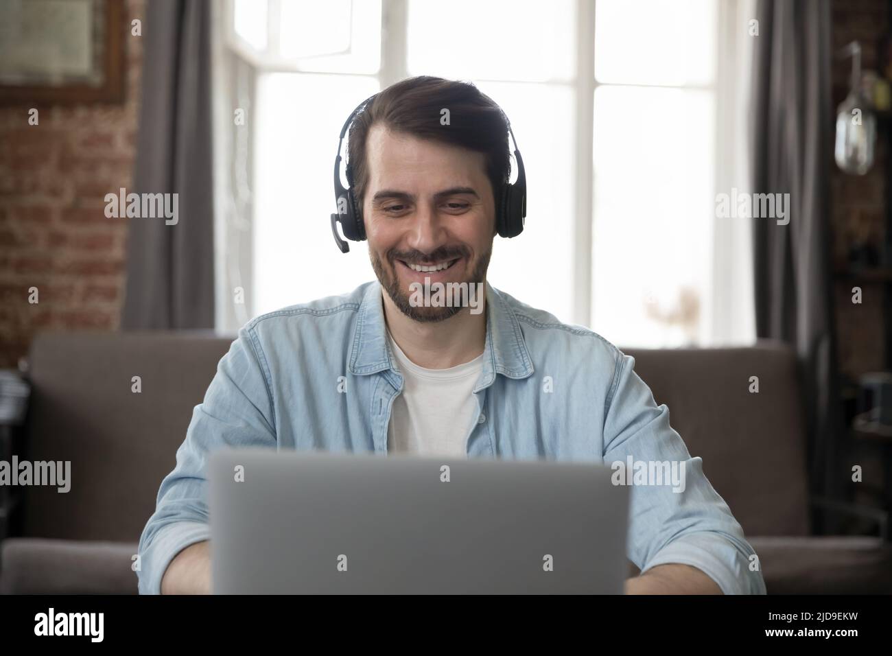 Homme d'affaires souriant porter un casque utiliser un ordinateur portable pour communiquer par vidéoconférence Banque D'Images