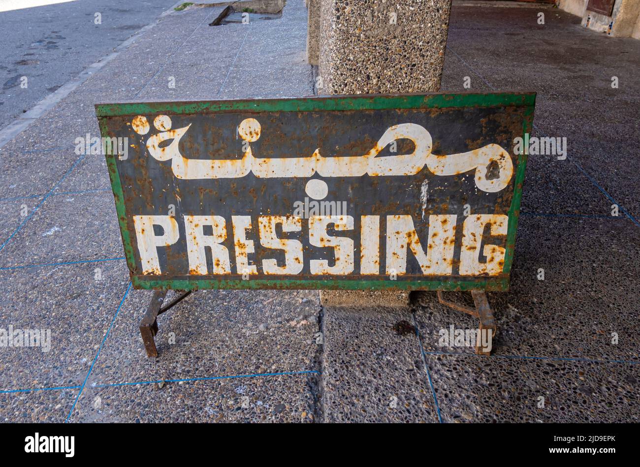 Panneau de presse, panneau de services de repassage sur la route dans la rue, arabe et français, Essaouira, Maroc Banque D'Images