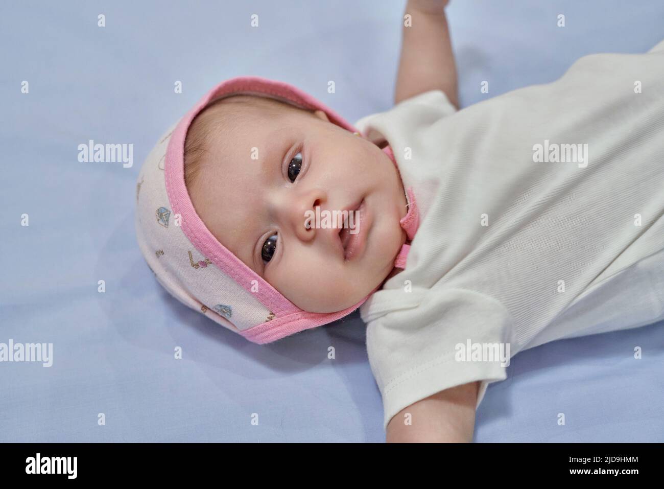 Petite fille avec serre-tête à fleurs blanc. bébé fille de 2 mois. Banque D'Images