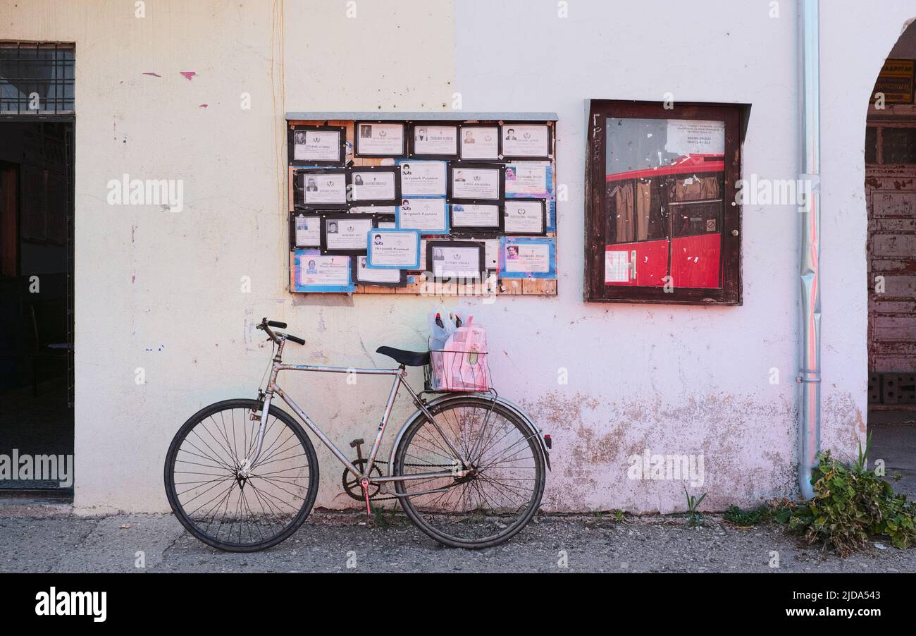 Façade avec tableau nécrologique et vieux vélo en Serbie Banque D'Images