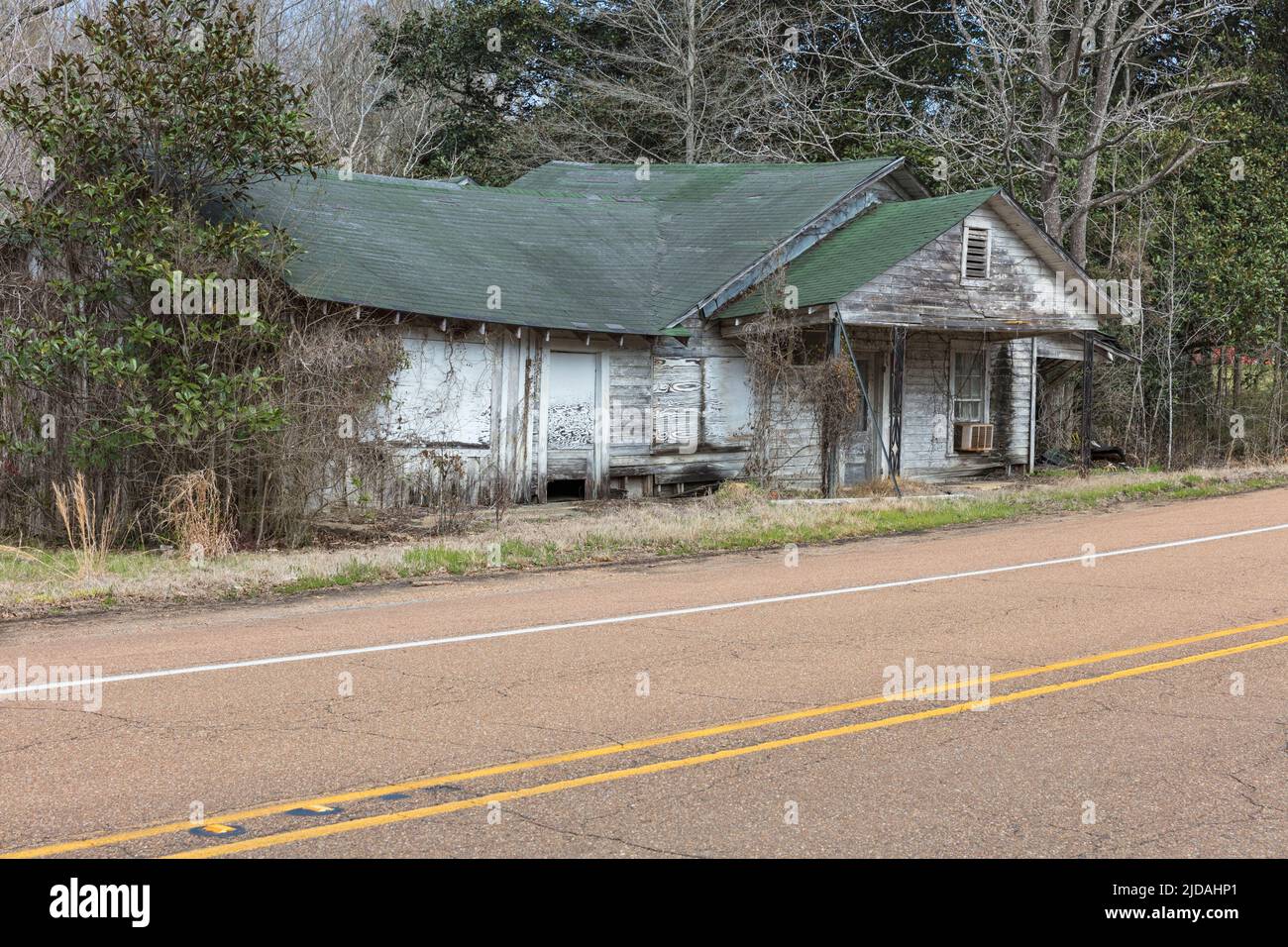 Une ferme rurale ou une petite maison abandonnée et en ruine, surcultivée avec des plantes et des arbustes. Banque D'Images