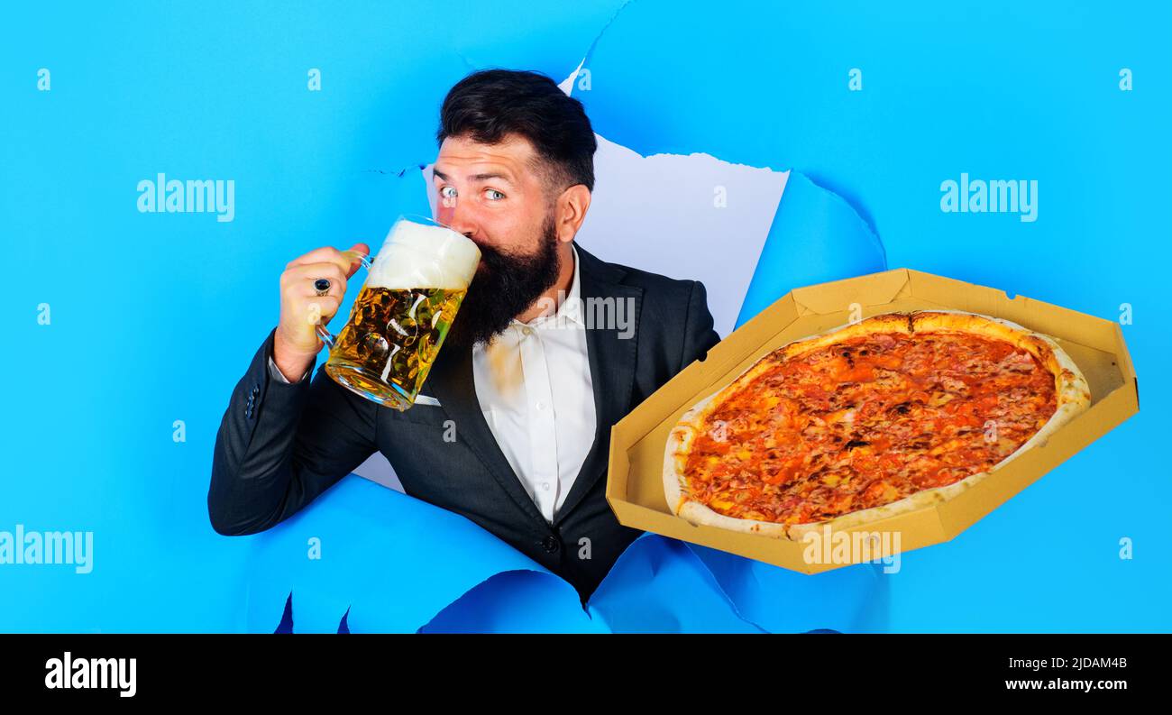 Homme barbu avec une délicieuse pizza buvant de la bière en regardant à travers le trou de papier. Cuisine italienne. Livraison de pizza. Banque D'Images