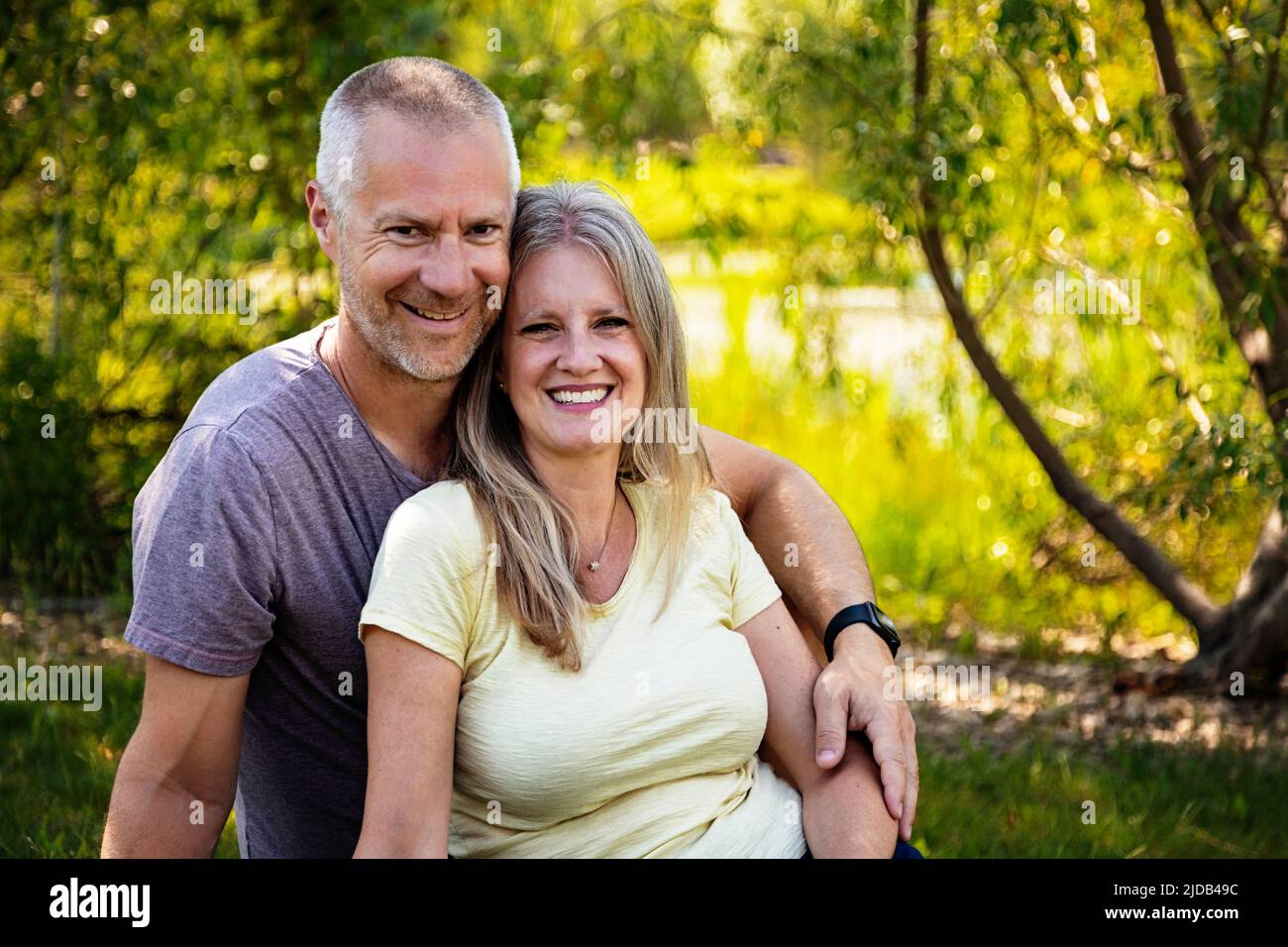 Portrait extérieur d'un couple marié mature assis sur l'herbe dans un parc; Edmonton, Alberta, Canada Banque D'Images