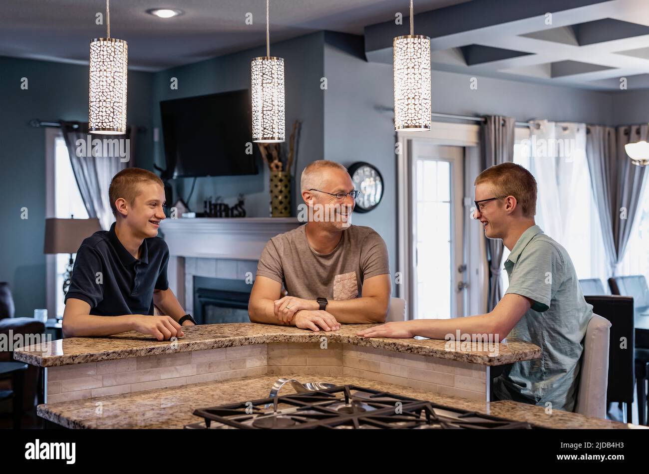 Le père et deux fils sont assis à l'île de la cuisine à la maison et parlent ensemble; Edmonton, Alberta, Canada Banque D'Images