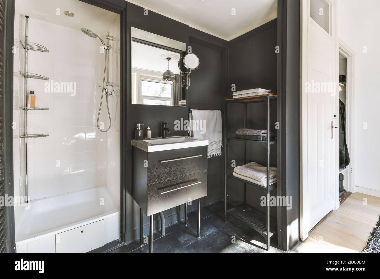 Salle de bains ouverte avec lavabo blanc et miroir sur mur noir, avec cabine de soufflerie dans appartement cher Banque D'Images