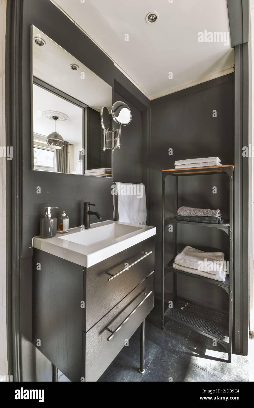 Un fragment de l'intérieur d'une salle de bains moderne noire avec un cabinet sous le lavabo, un miroir et une serviette Banque D'Images