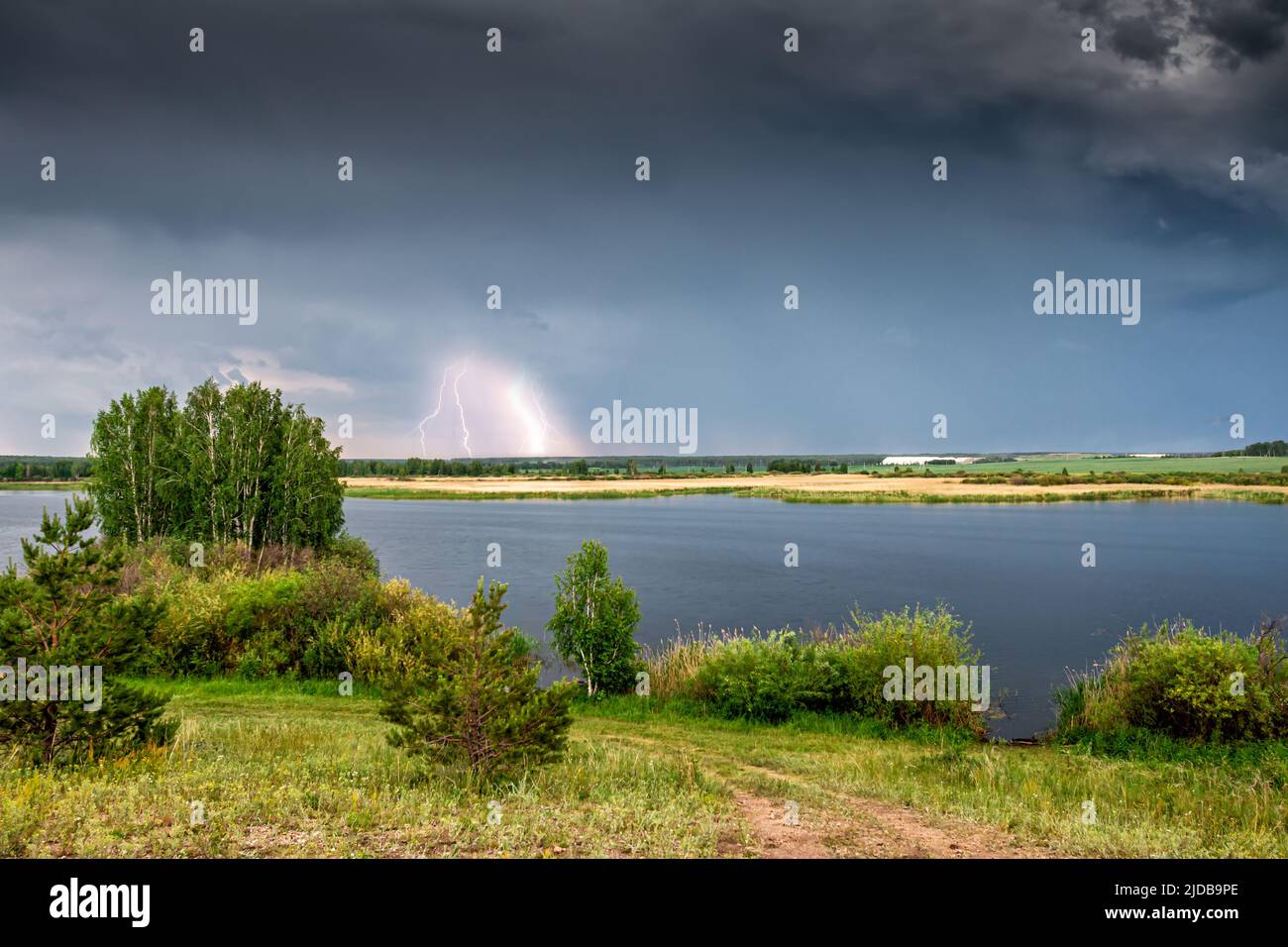 Pittoresque rive de la rivière par une journée nuageux. La foudre clignote à distance Banque D'Images