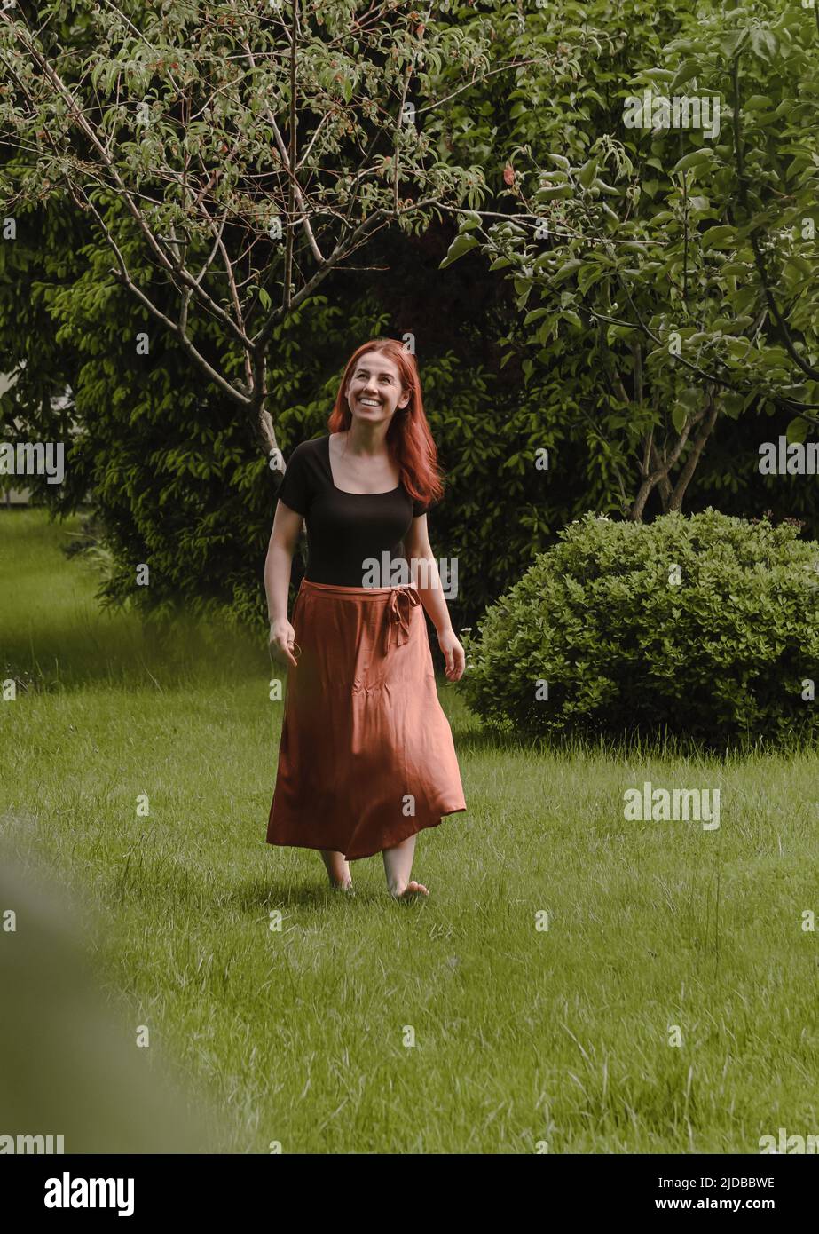 Joyeux cheveux de gingembre femme marchant pieds nus dans le parc ou le jardin. Liberté et mode de vie sain. Femme dans son 40s ayant le repos à l'extérieur. Personnes dans Banque D'Images