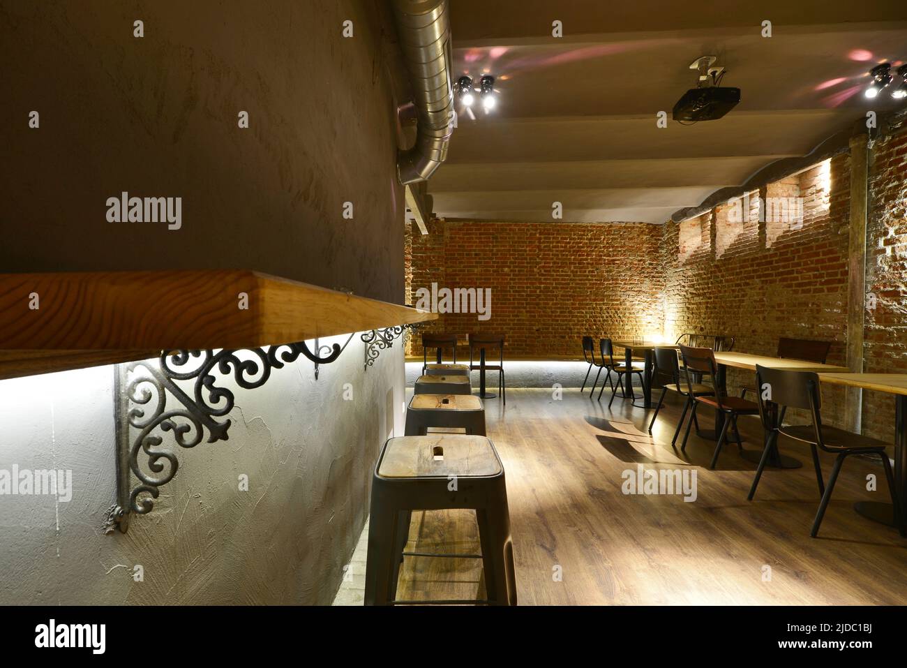 Salle à manger d'un restaurant avec miroirs sur les murs, tables en bois et sol assorti, tabourets en bois et en métal et murs en briques Banque D'Images