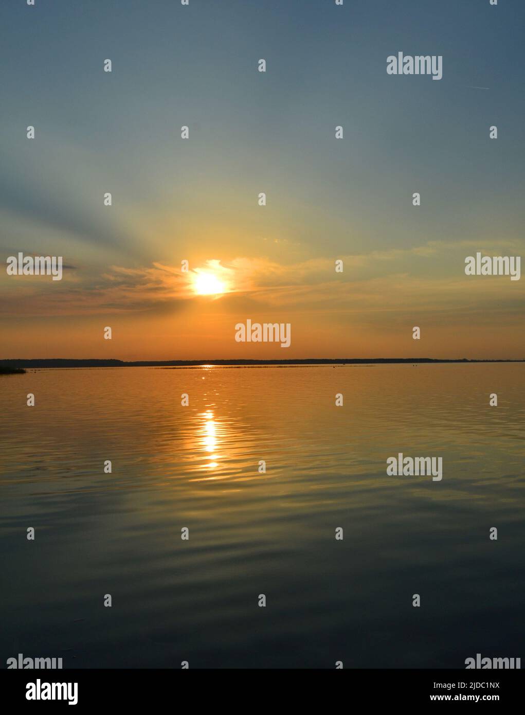 Magnifique coucher de soleil. Coucher de soleil romantique sur le lac. Paysage du soir. Nuages réfléchis dans l'eau. L'horizon au coucher du soleil. Mer, lac au coucher du soleil. Les vagues Banque D'Images
