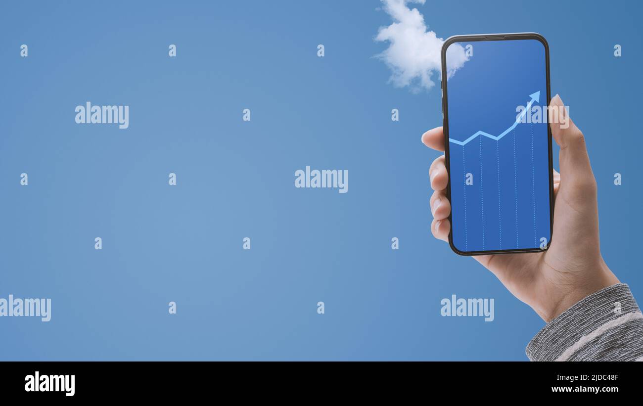 Main tenant un smartphone et graphique financier montrant la croissance sur l'affichage, ciel bleu dans l'arrière-plan, espace de copie vierge, plan de POV Banque D'Images