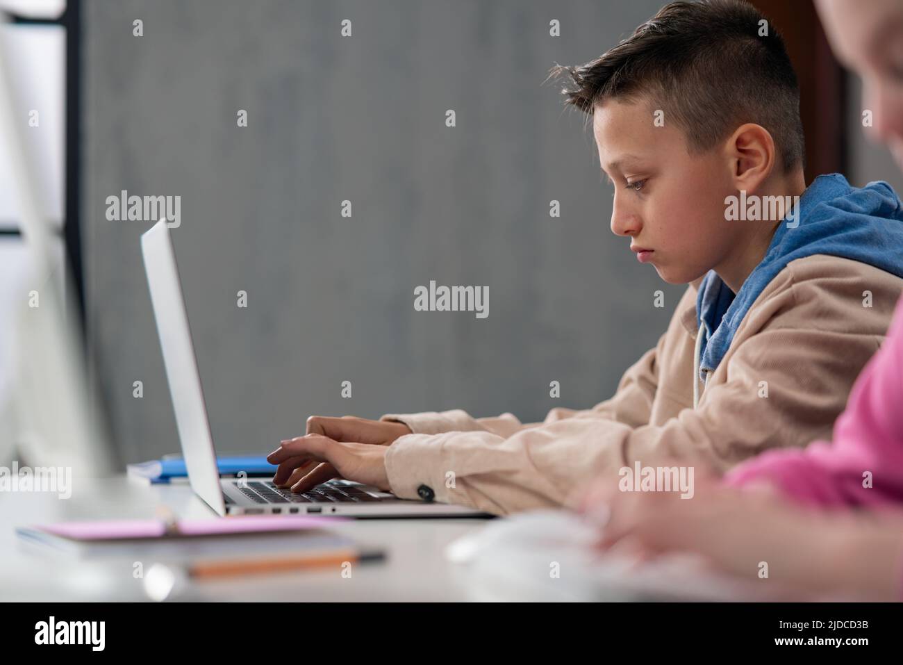 Vue latérale de l'élève en utilisant l'ordinateur dans la salle de classe à l'école Banque D'Images