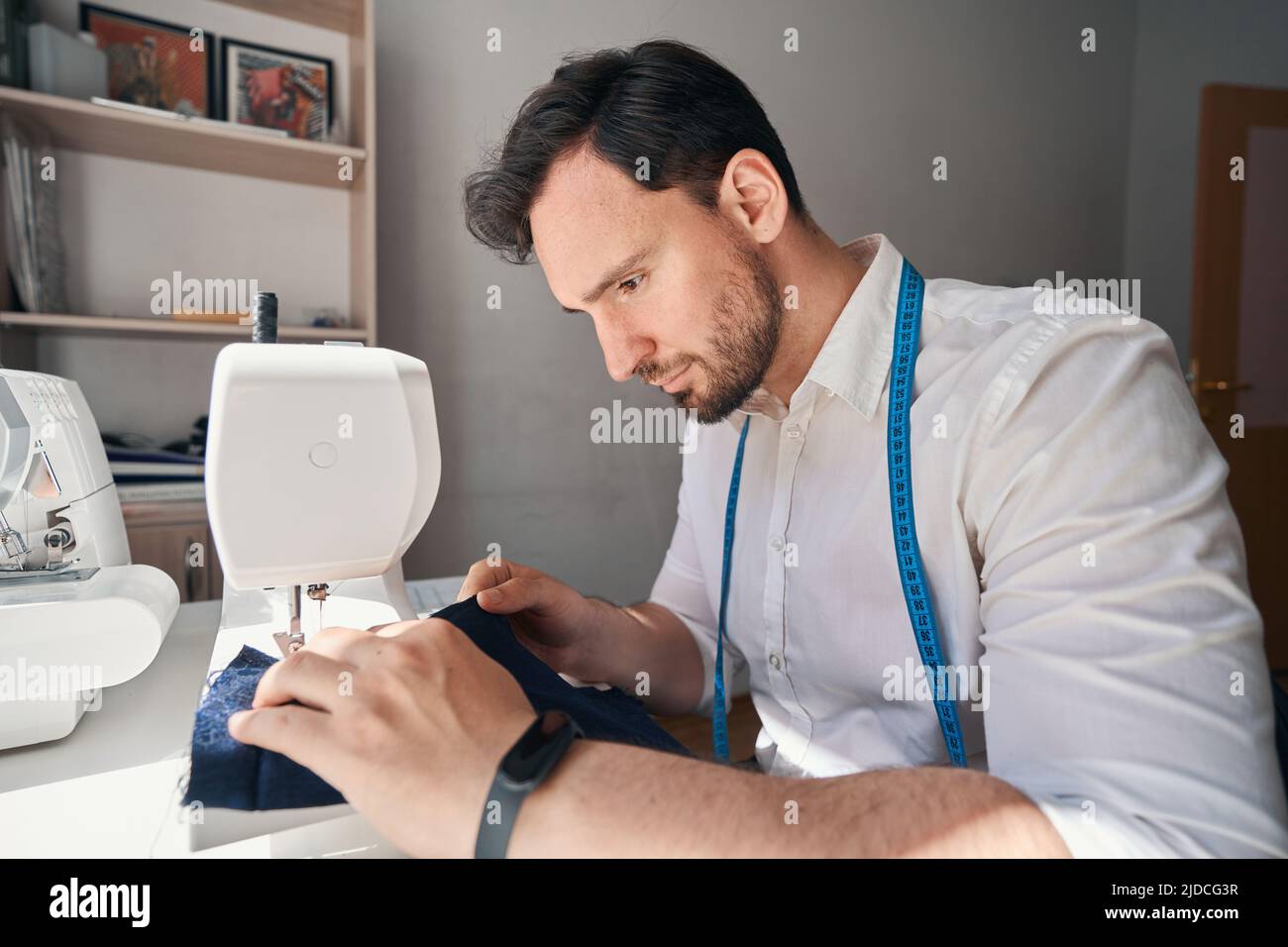 Jeune homme coudre des vêtements avec une machine professionnelle Banque D'Images