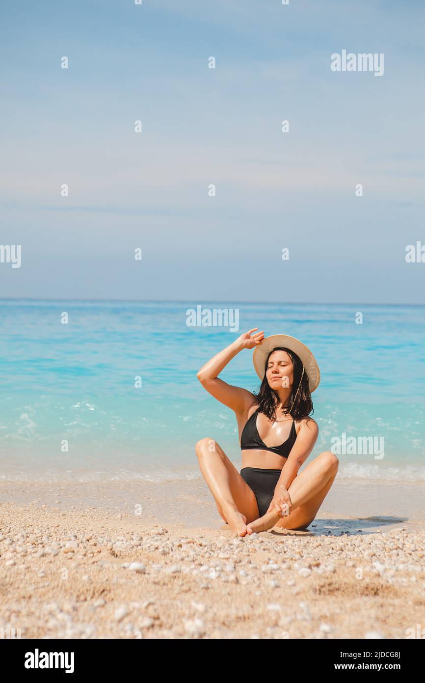 femme en chapeau blanc et maillot de bain noir en bleu eau de mer vacances d'été Banque D'Images